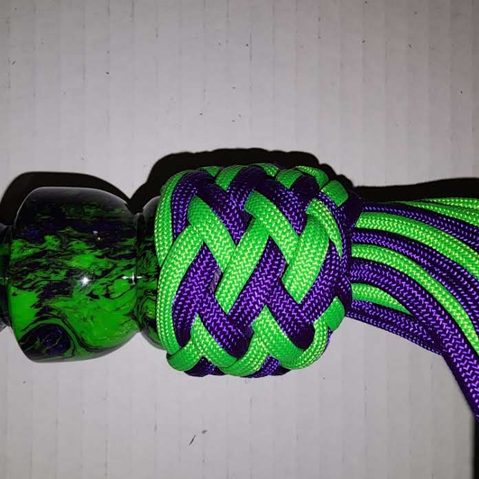 Purple and green acrylic handled flogger with purple and green paracord falls