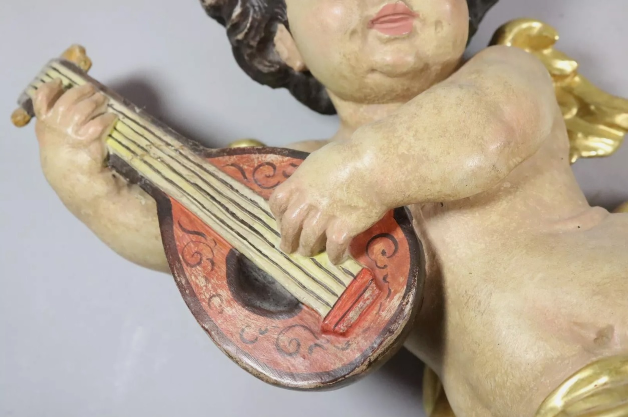 Figura de querubín en madera tallada y policromado con instrumento musical