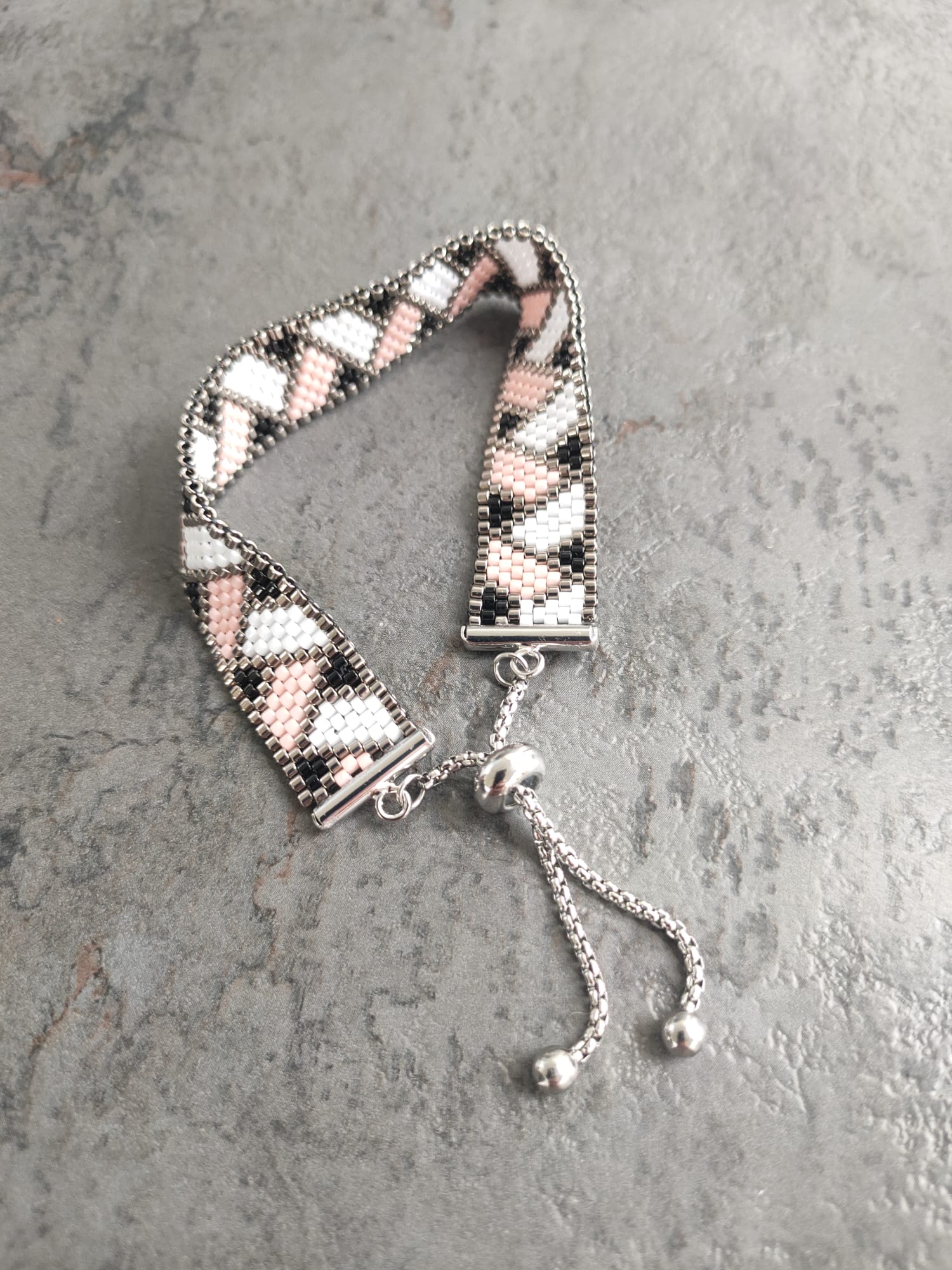 Bracelet tissé avec 800 perles argentées roses et noires .