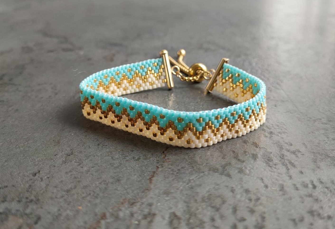 Bracelet tissé avec 640 perles dorées bleues et crèmes .