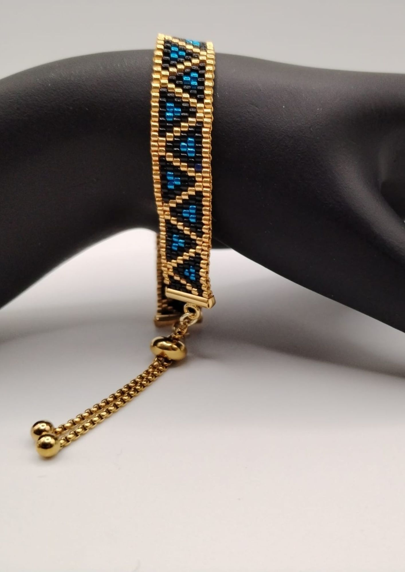 Bracelet tissé avec 640 perles dorées noires et bleues .