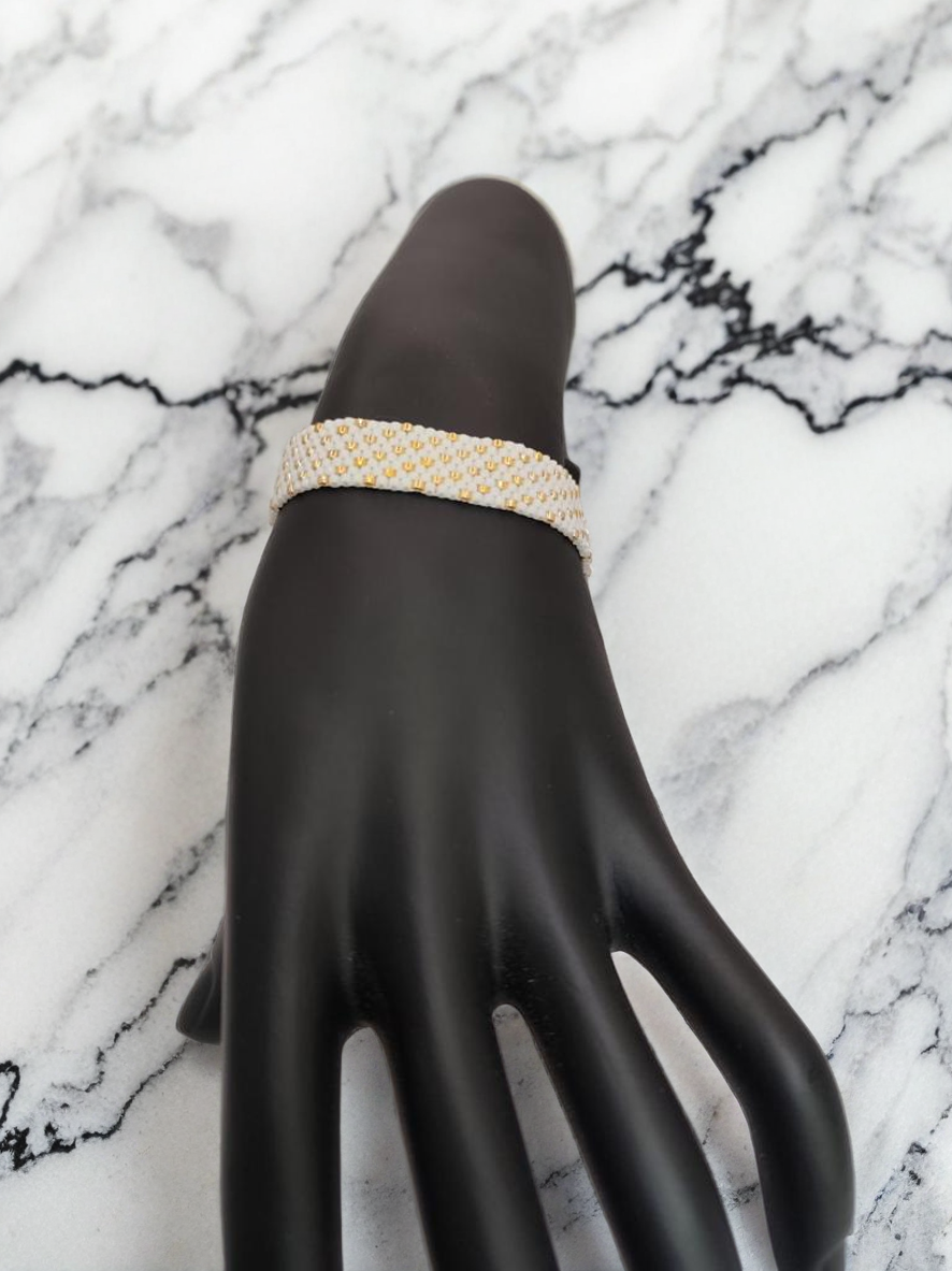 Bracelet tissé avec 640 perles blanches et dorées .