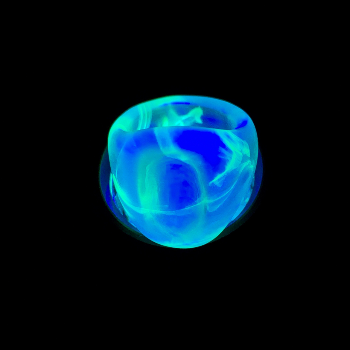 Floating green jadeite cabochon ring with glowing in the dark resin band