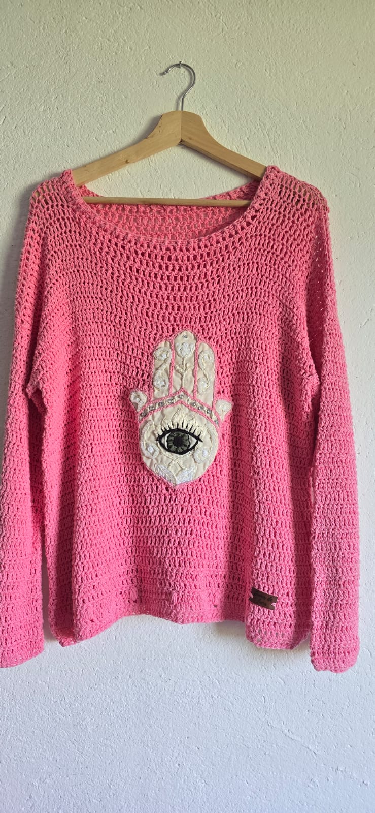 Suéter tejido rosa con diseño de mano y ojo