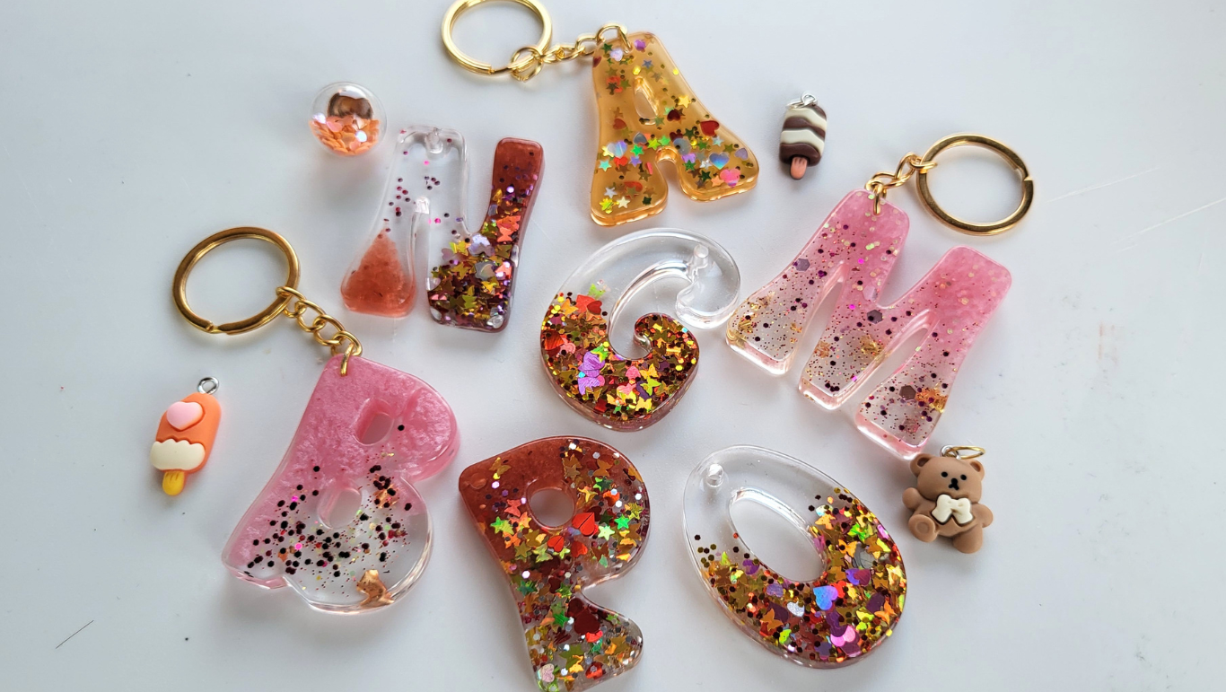 Llavero de letra con colores y purpurina; con 2 acesorios y bolsita regalo. 