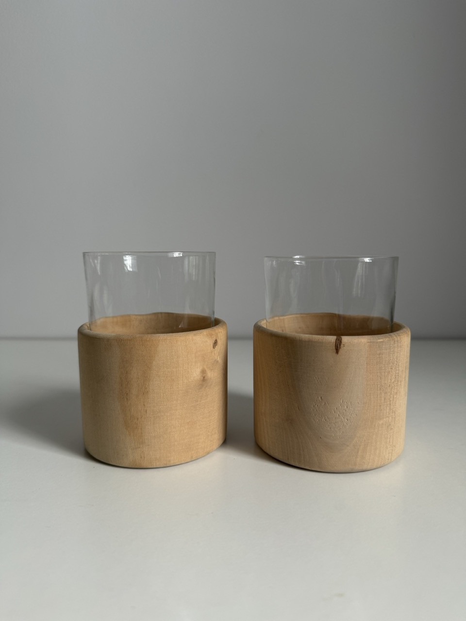 A pair of glass cups with handmade wooden coasters by the Finnish brand Aarikka