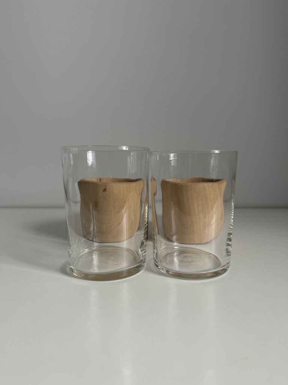 A pair of glass cups with handmade wooden coasters by the Finnish brand Aarikka