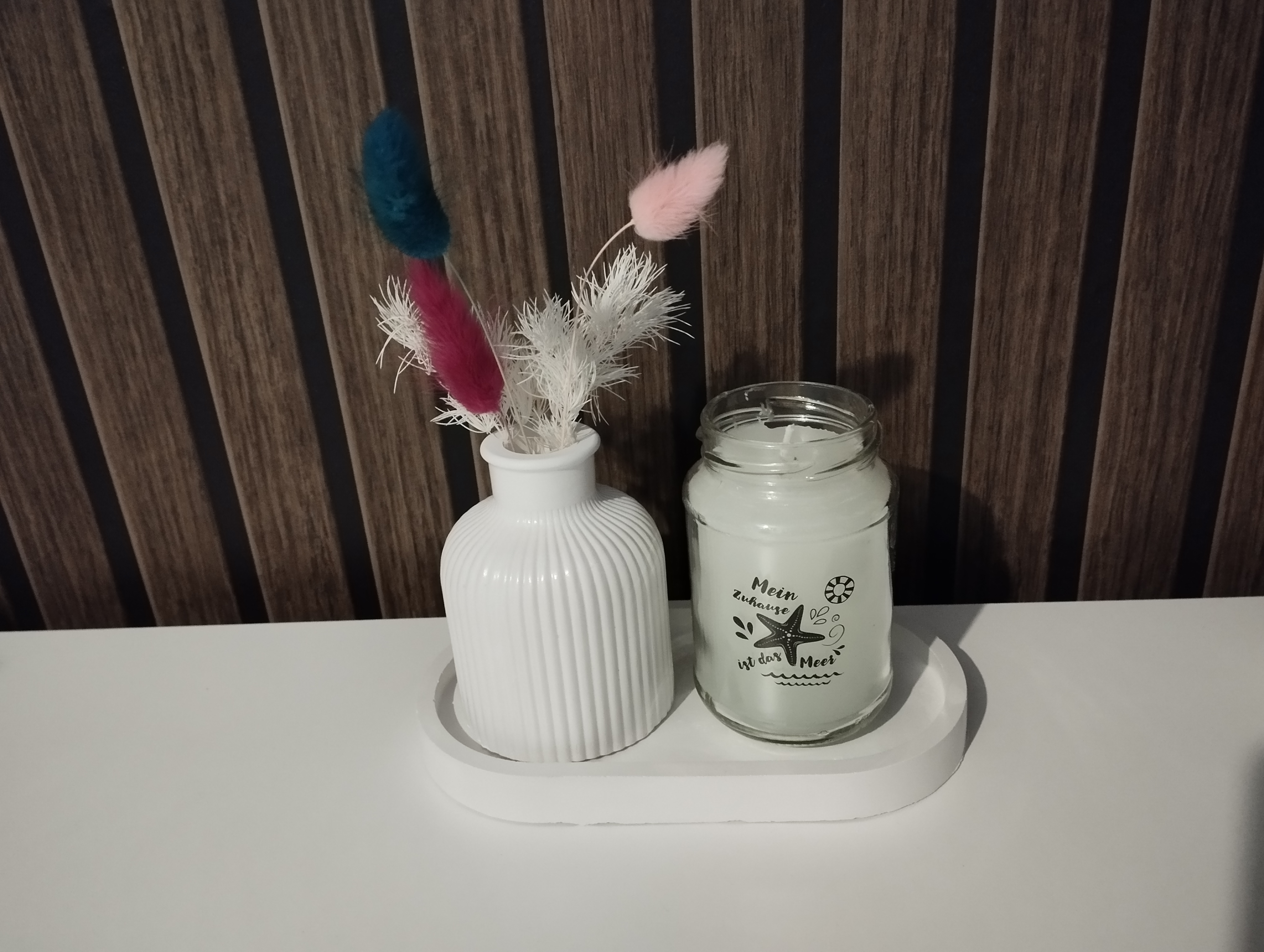 Vase mit Stumpenkerze auf ovalen Tablett