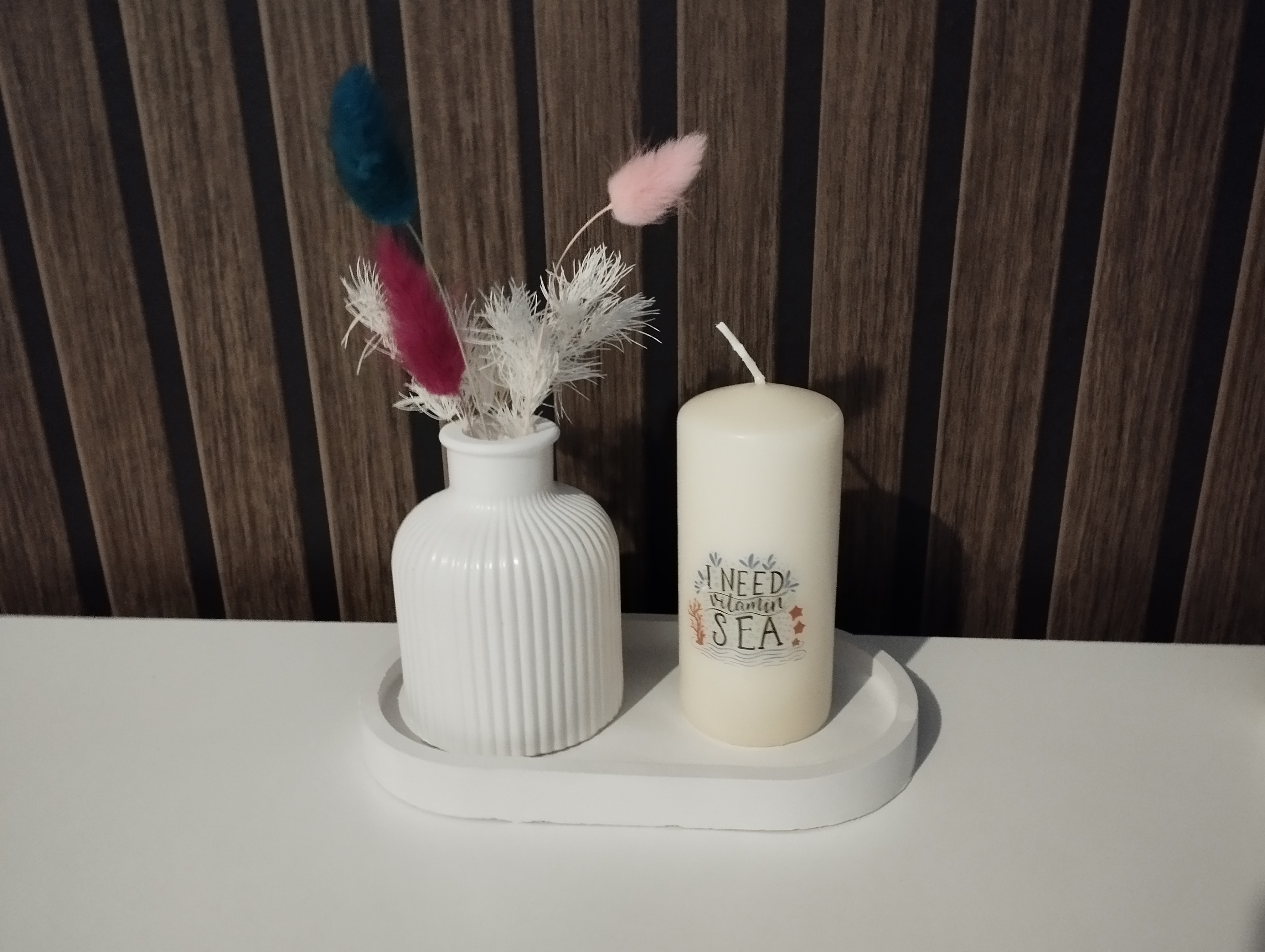 Vase mit Stumpenkerze auf ovalen Tablett