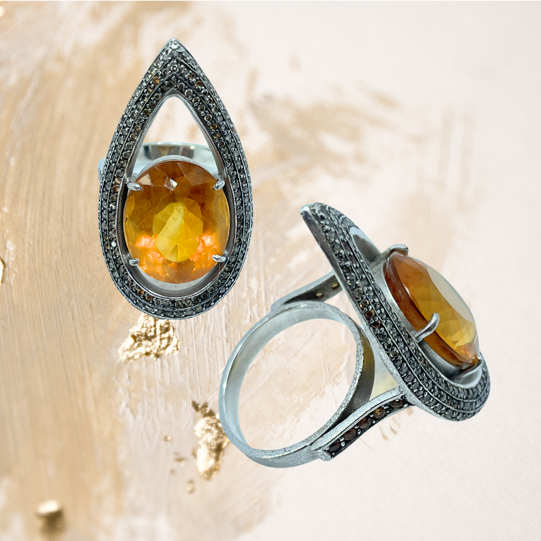 Este anel em prata revela o brilho intenso de uma pedra preciosa oval em tom laranja vibrante.