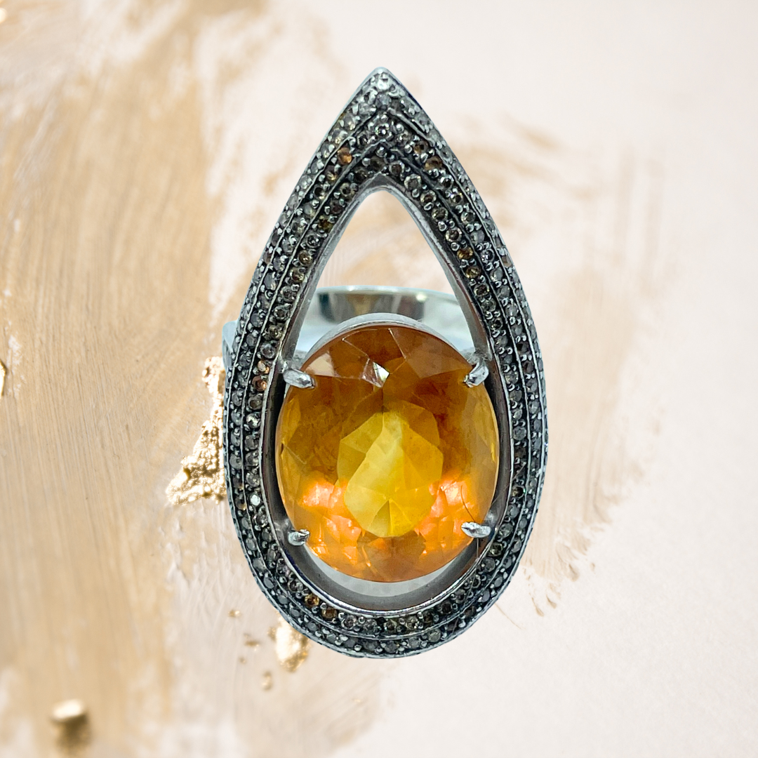Este anel em prata revela o brilho intenso de uma pedra preciosa oval em tom laranja vibrante.