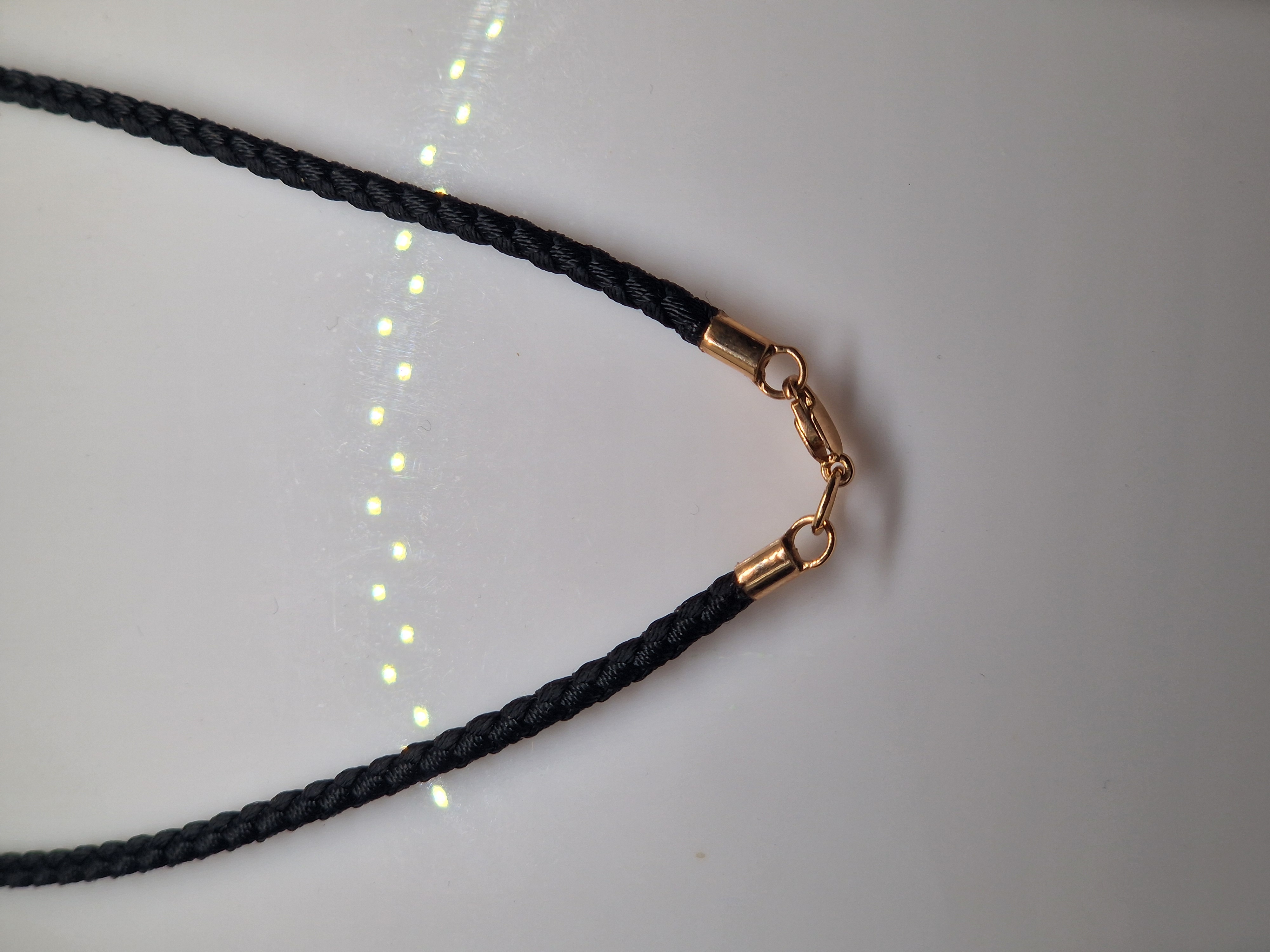 Black syntetic cord with gold ends and a lock