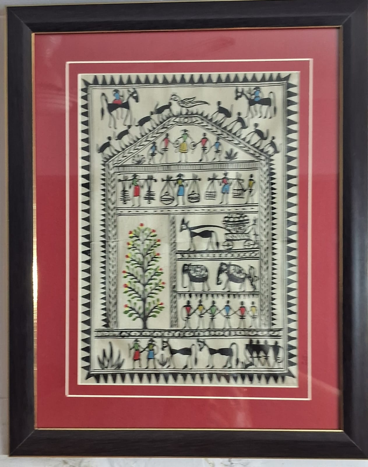 Traditional Indian Madhubani Art created by local artist in a golden and brown wooden frame.