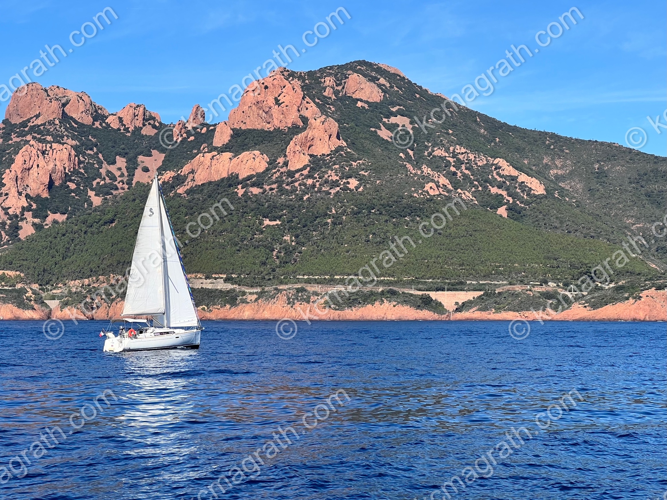 Cannes - St. Tropez Waters with White Sailboat and Sunlit-Pink Mountains, France