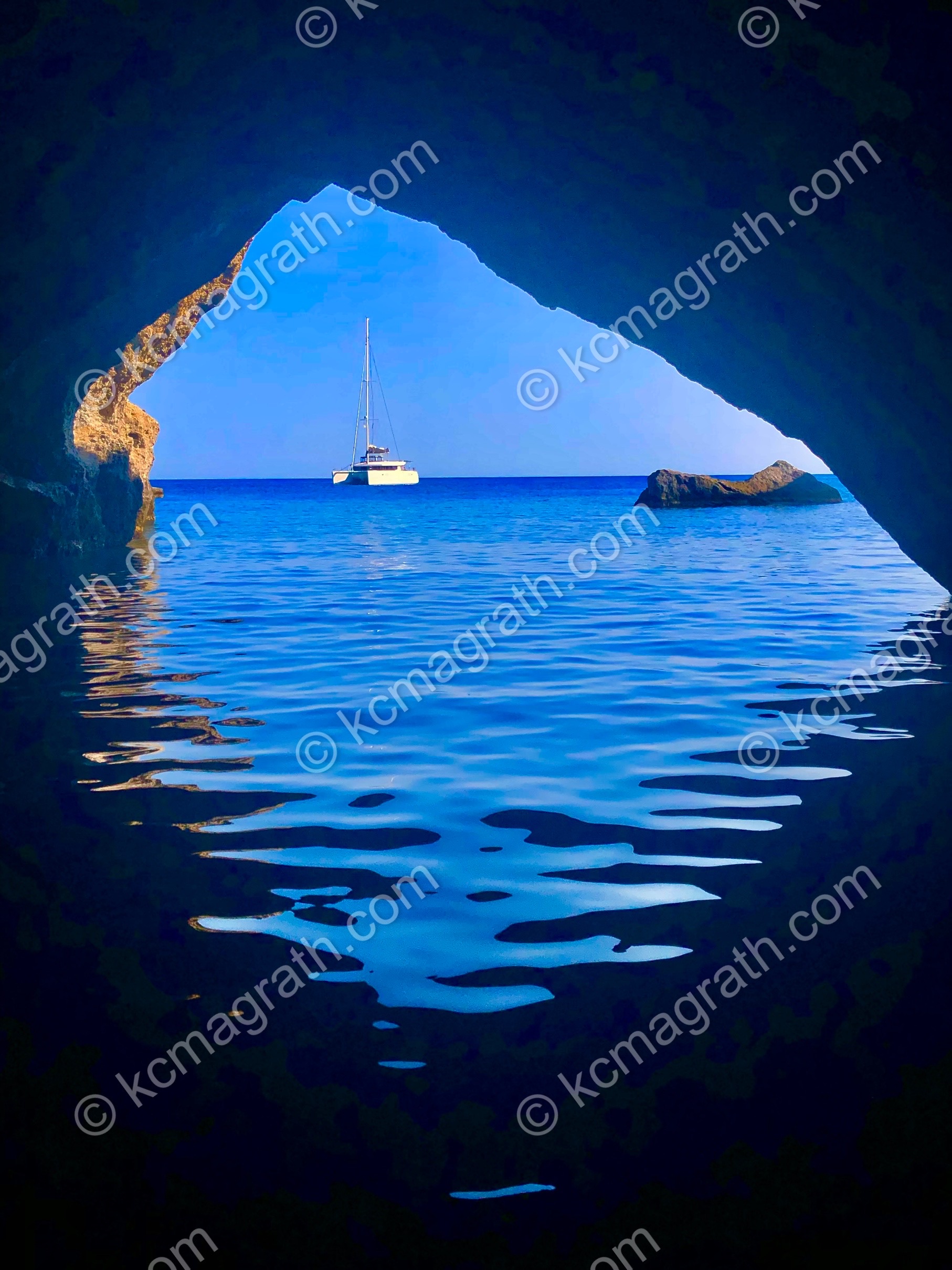 Milos's  Med Blue Waters and White Sailboat (S/V Desert Rose), Taken From Inside a Cave, Greece