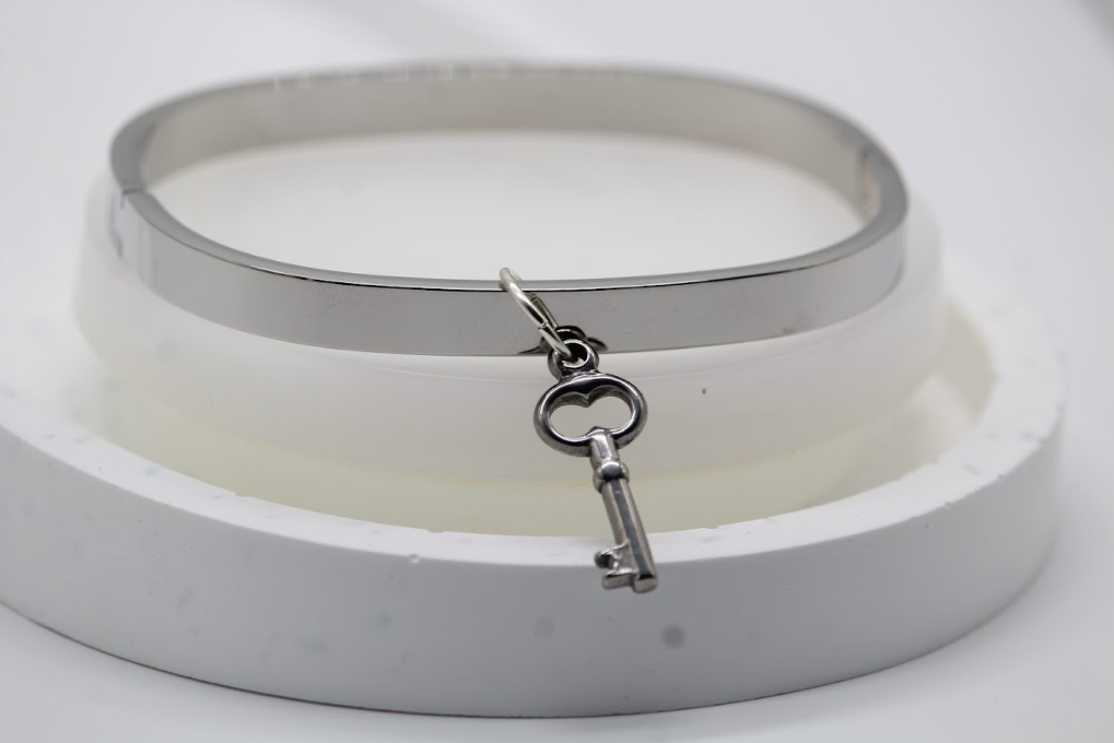 Pulsera tipo brazalete dorada con dije de llave