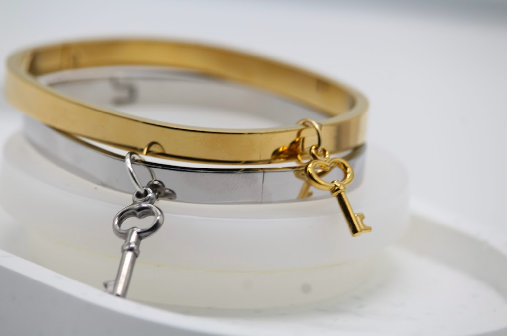 Pulsera tipo brazalete dorada con dije de llave