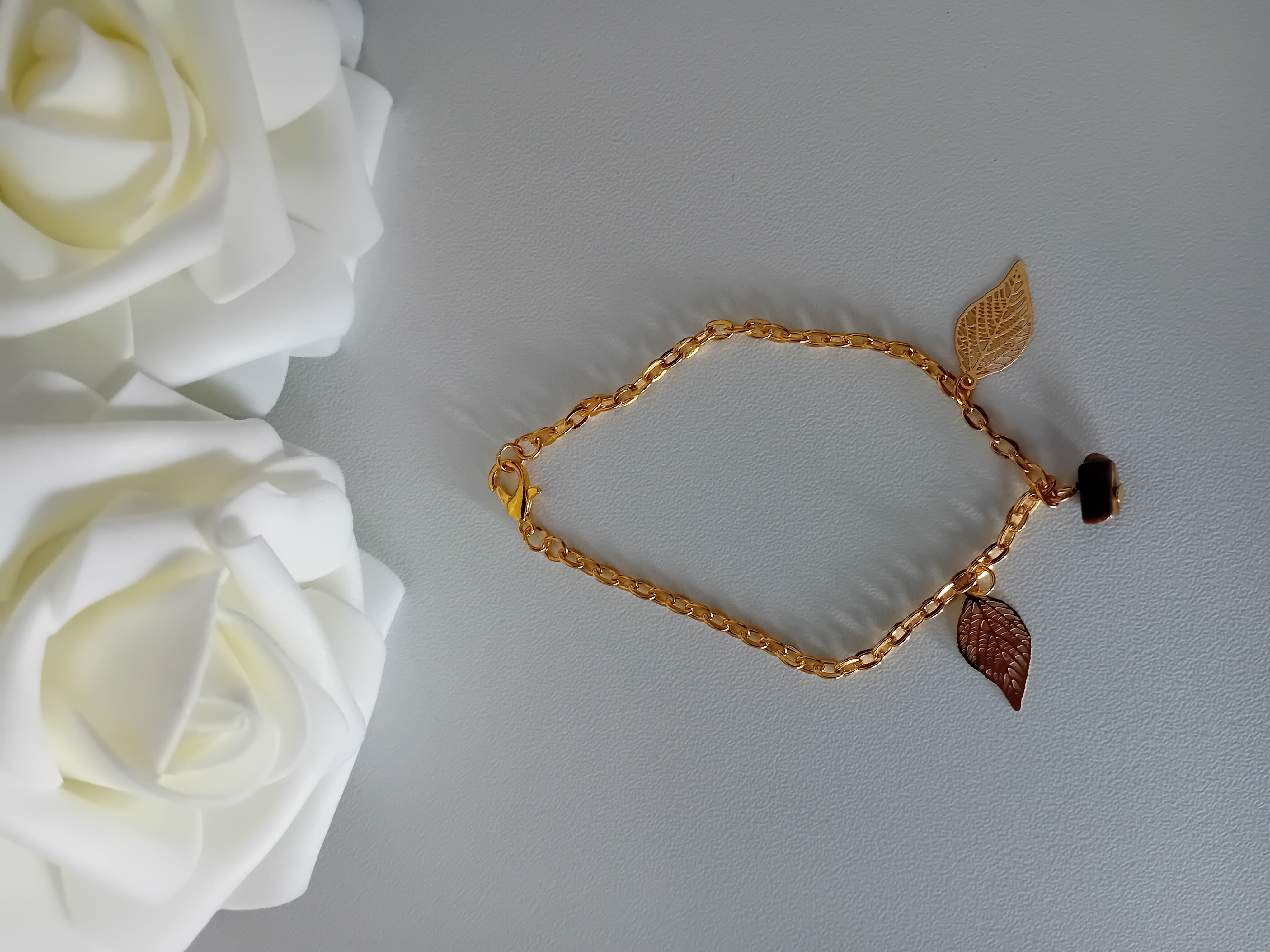 Bracelet doré avec sa perle marron œil de tigre et ses deux pendentifs feuilles. Un bijou élégant pour chaque jours.