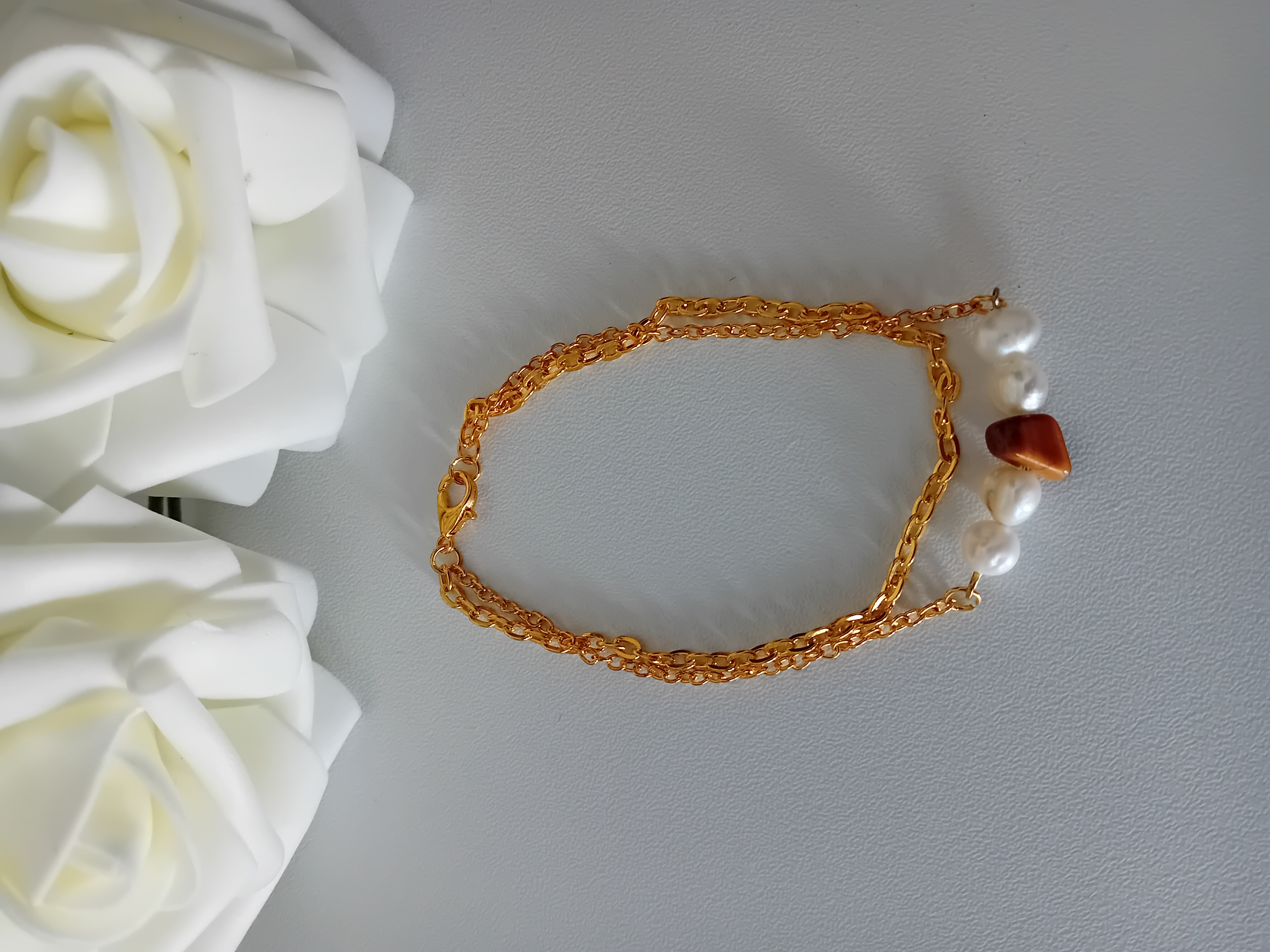 Bracelet doré avec perles nacrées et sa perle marron œil de tigre avec ses deux chaînes. Idéal pour toutes les occasions.