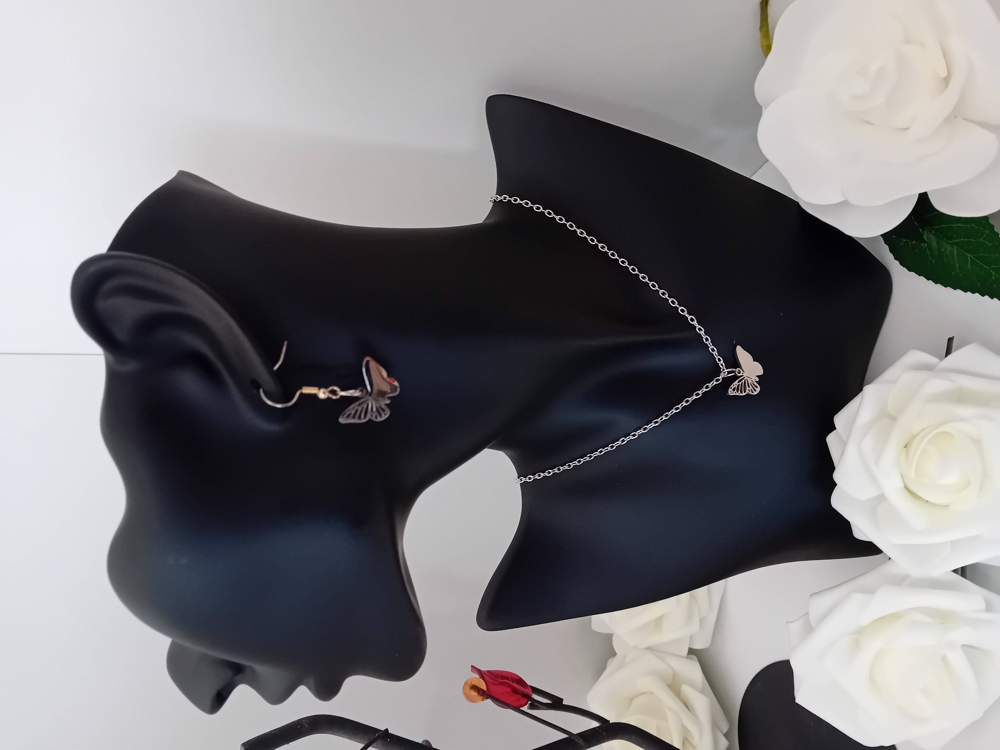 Ensemble collier et boucle d'oreille papillon argentée.