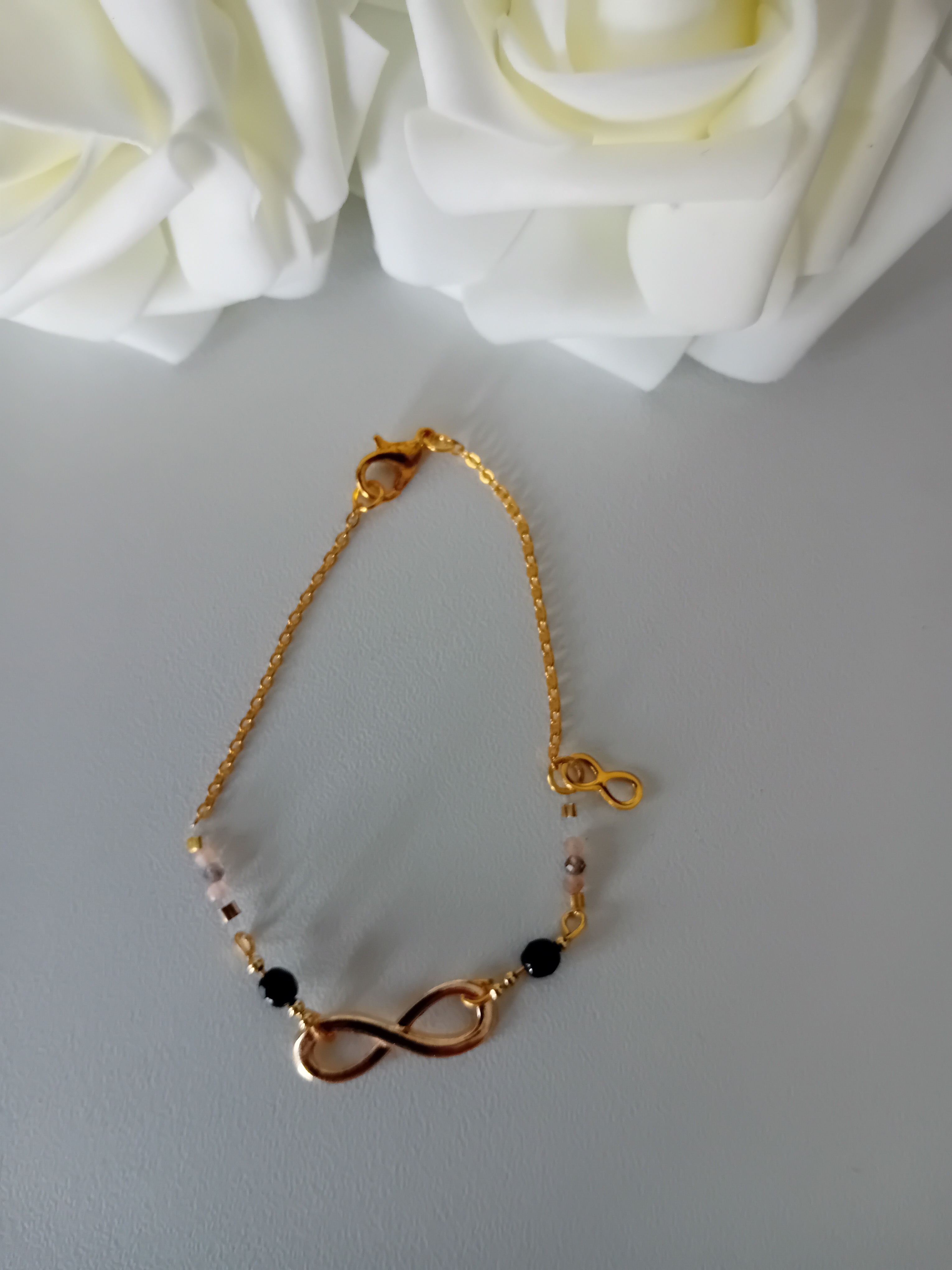 Bracelet infini doré. Bijou raffiné avec perles et pendentif infini.