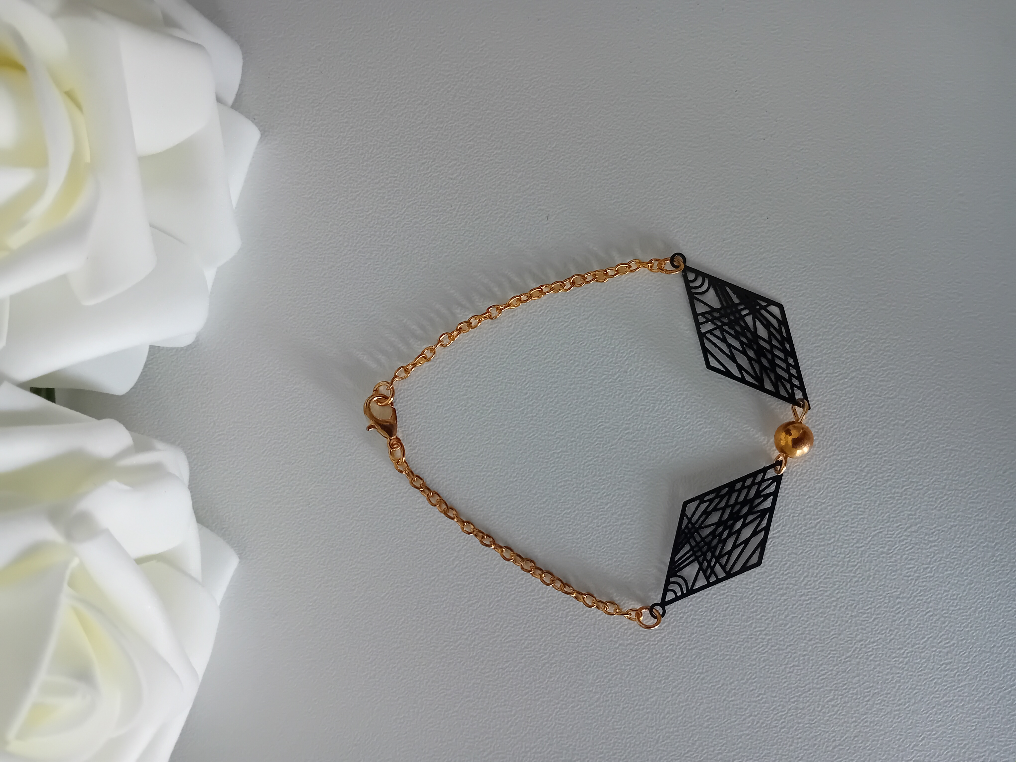 Bracelet élégant en chaîne dorée. Bijou raffiné avec des motifs géométriques en filigrane noir