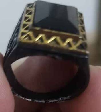 Metal ring with black stone and golden frame