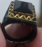 Metal ring with black stone and golden frame