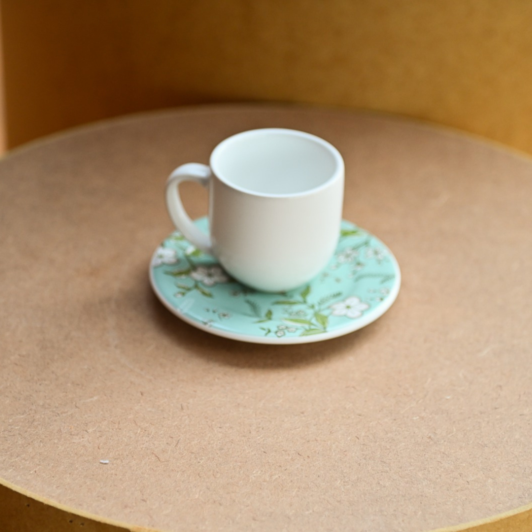 Xícara de café com pires floral em fundo azul claro