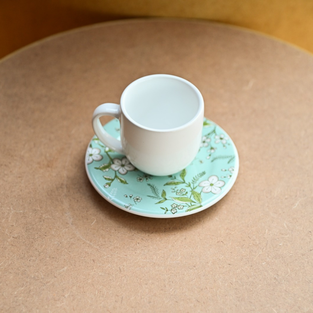 Xícara de café com pires floral em fundo azul claro