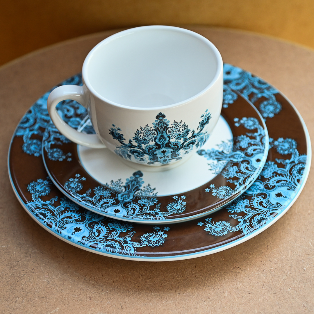Conjunto com xícara, pires e prato de sobremesa em porcelana com estampa floral azul e fundo marrom