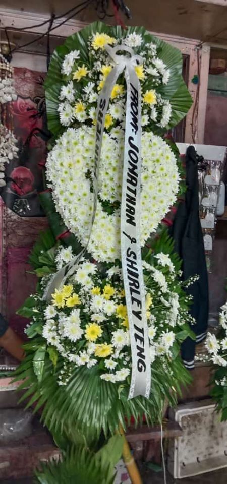 Heart-shaped condolence wreath with white and yellow flowers