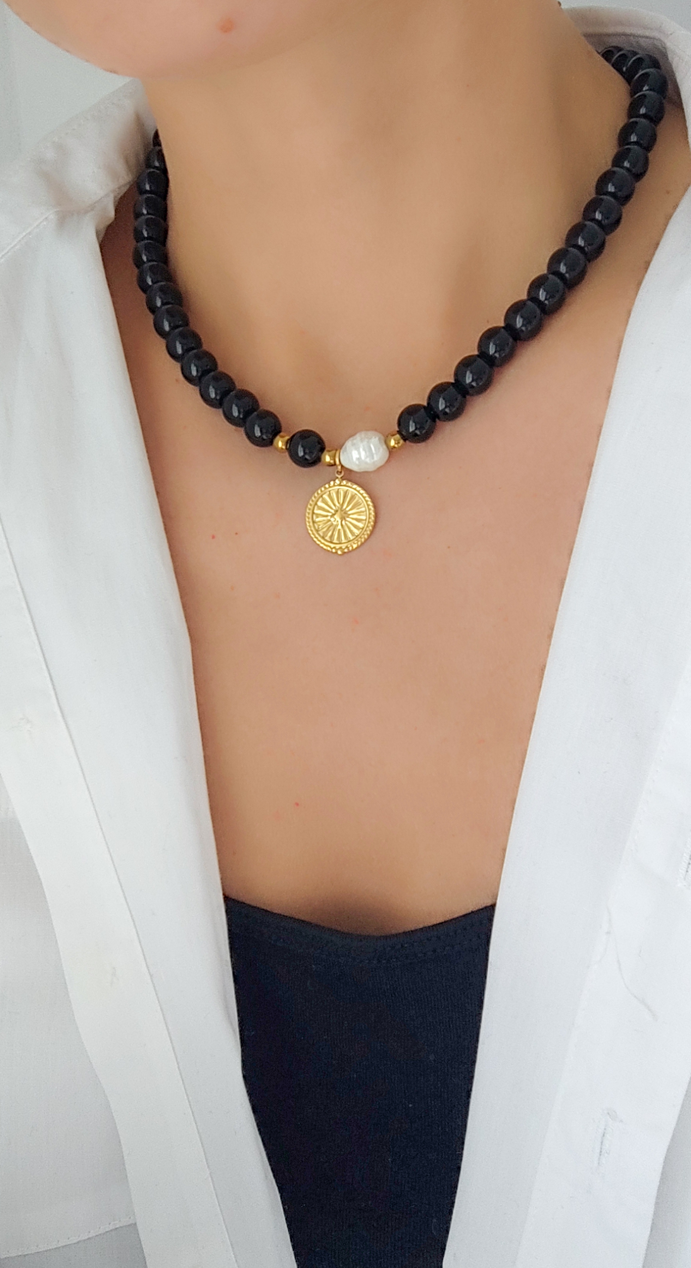 Juodų akmenukų vėrinys su auksiniu pakabuku