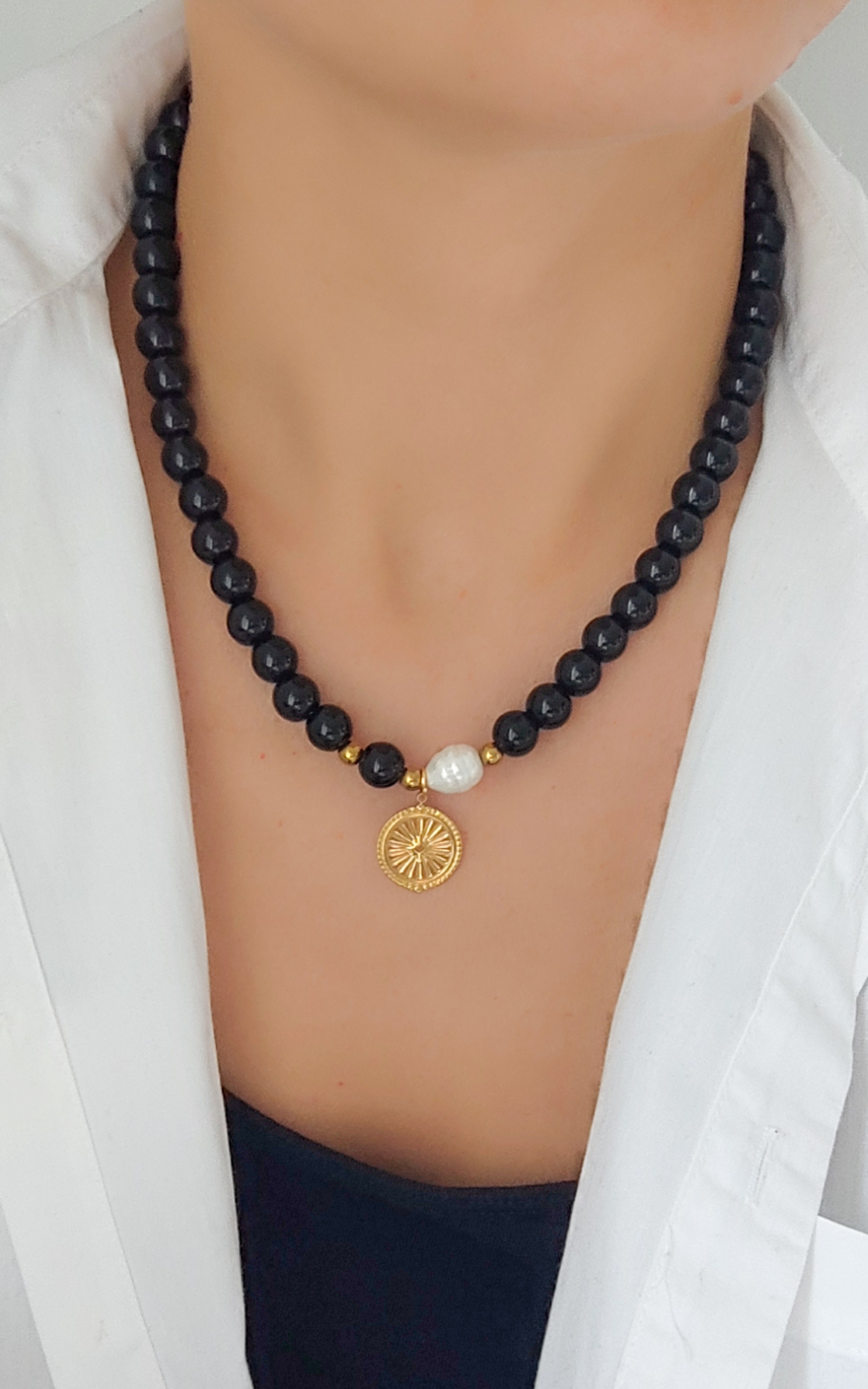 Juodų akmenukų vėrinys su auksiniu pakabuku