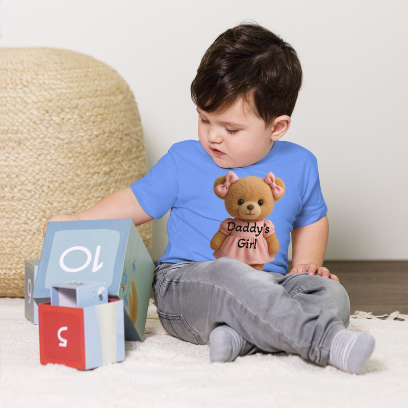 Toddler Short Sleeve Tee Daddy's Girl. This lovable T-shirt features an adorable teddy bear dressed in soft pink from head to toe—pink bows, pink dress, and tiny pink sneakers—capturing the perfect “D