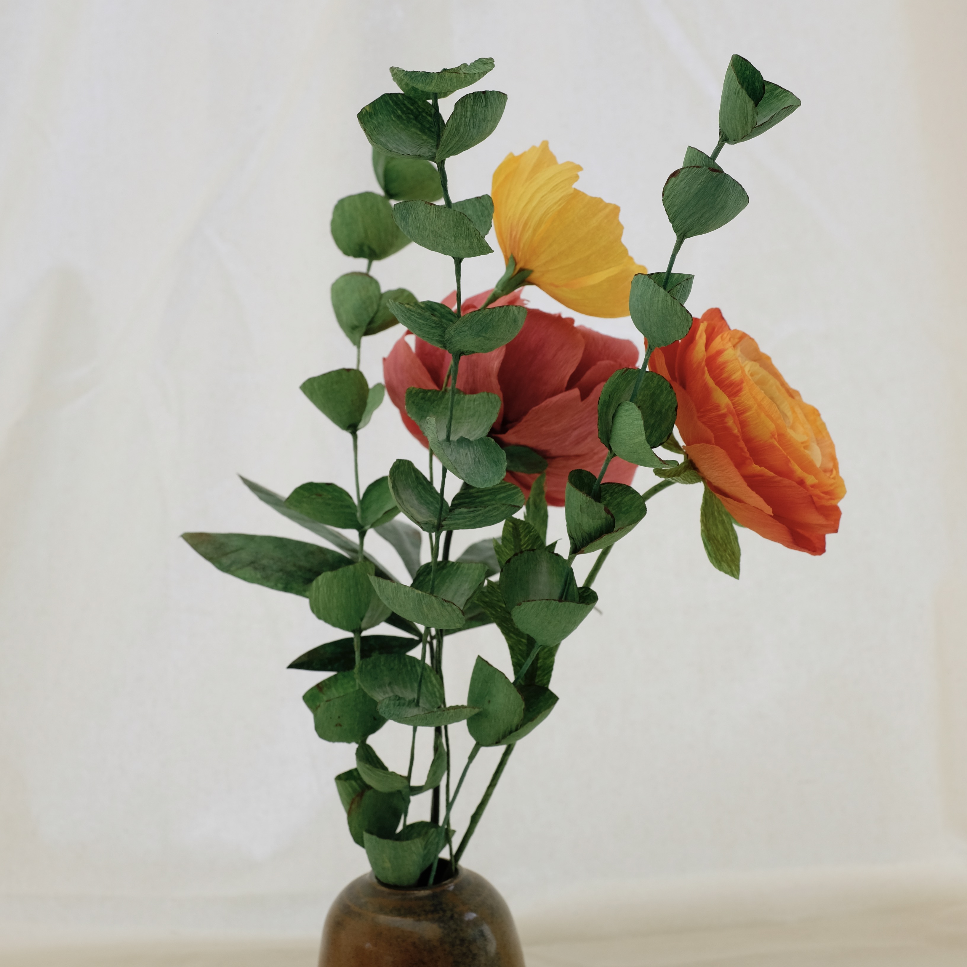 Bouquet de fleurs en papier : pivoine rose, renoncule orange, cosmos jaune, et trois brins d'eucalyptus