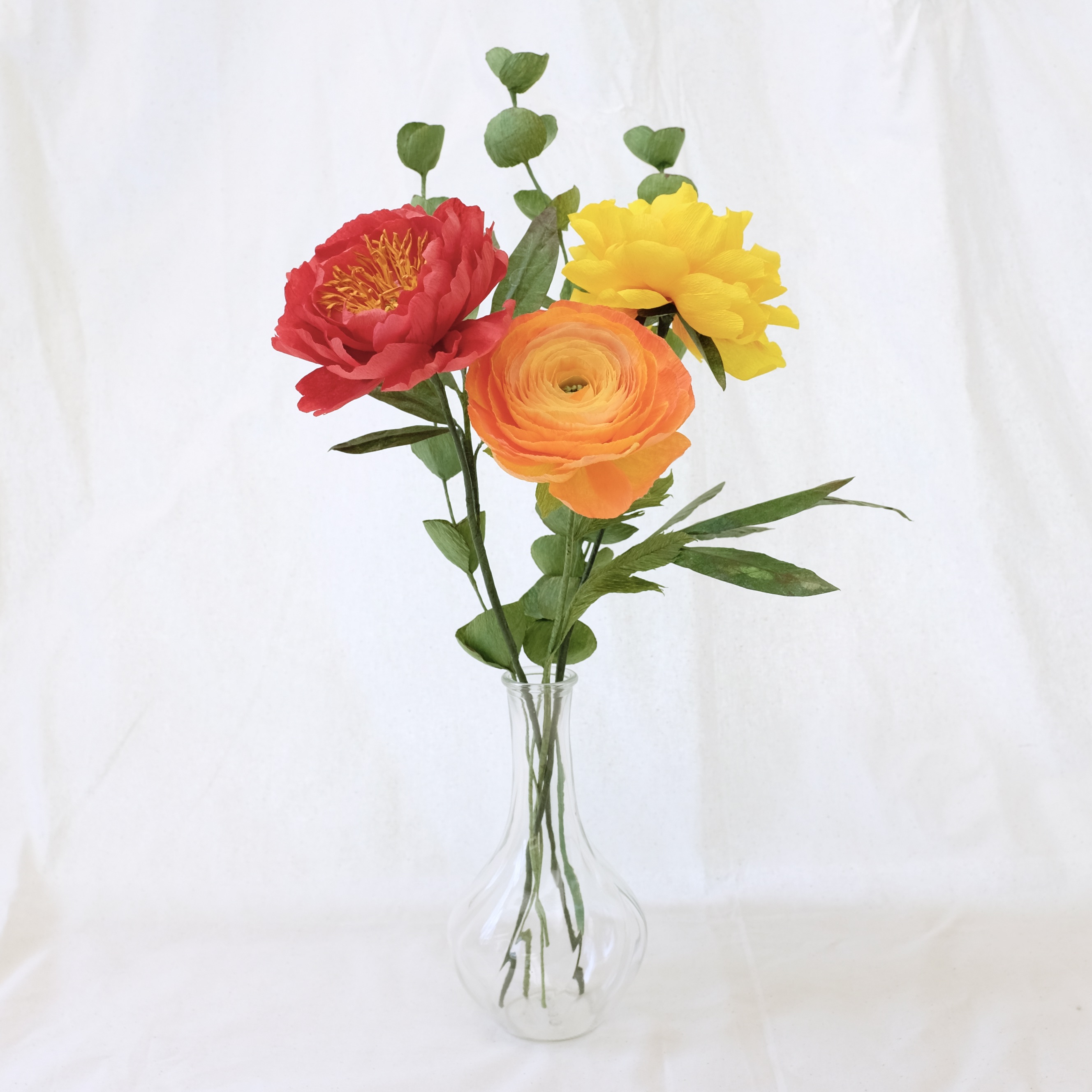 Bouquet de fleurs en papier : pivoine rouge, pivoine jaune,  renoncule orange et trois brins d'eucalyptus