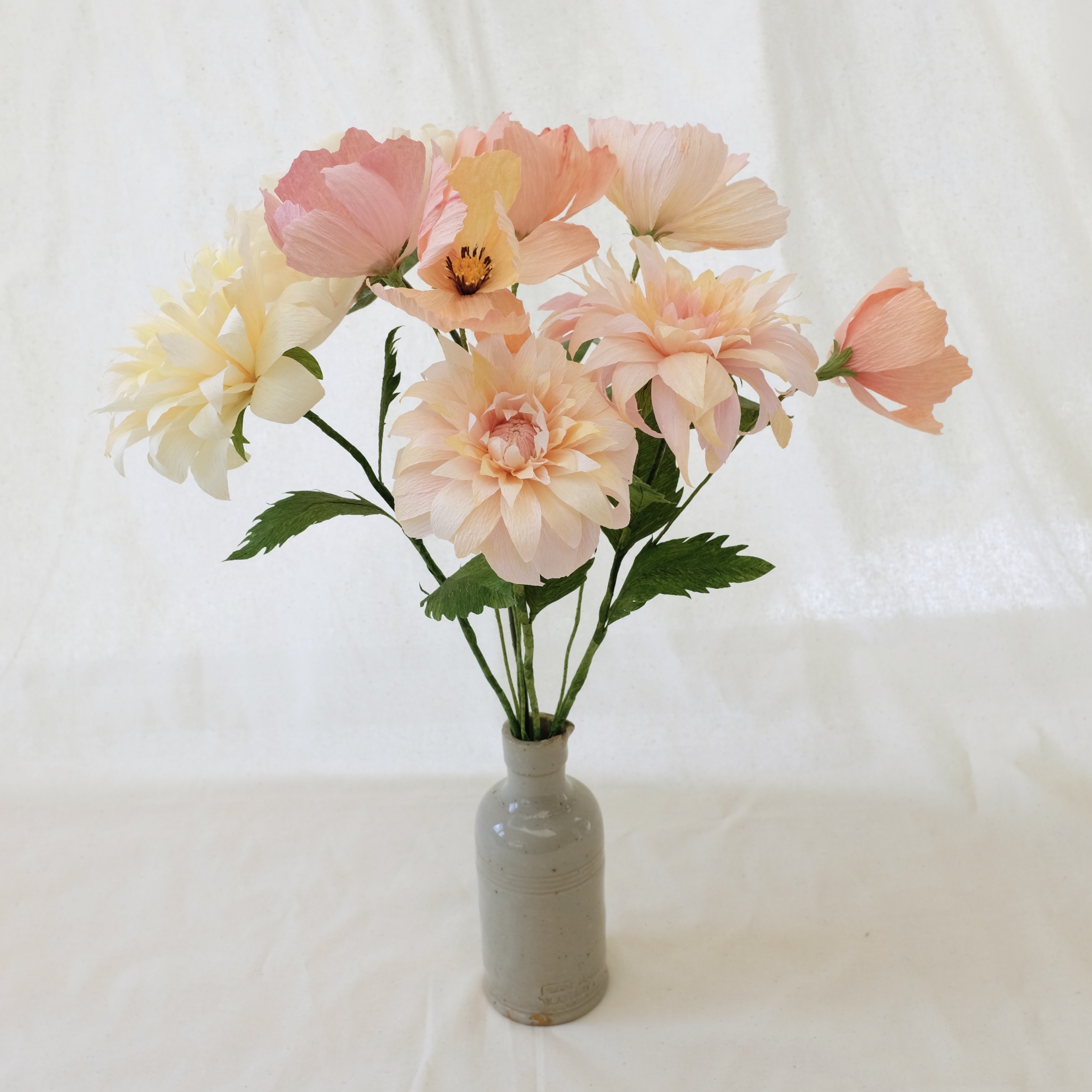 Bouquet de fleurs en papier tons pastels : pivoine blanche, deux dahlias rose poudré, un dahlia crème, cinq cosmos tons pastels
