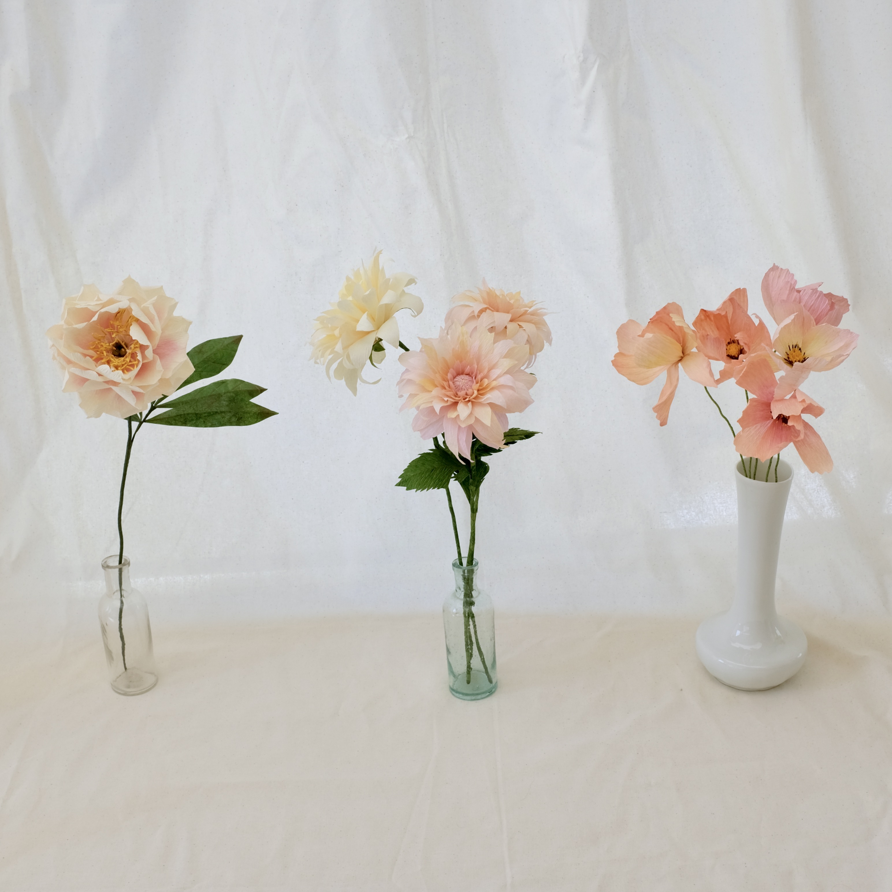 Bouquet de fleurs en papier tons pastels : pivoine blanche, deux dahlias rose poudré, un dahlia crème, cinq cosmos tons pastels