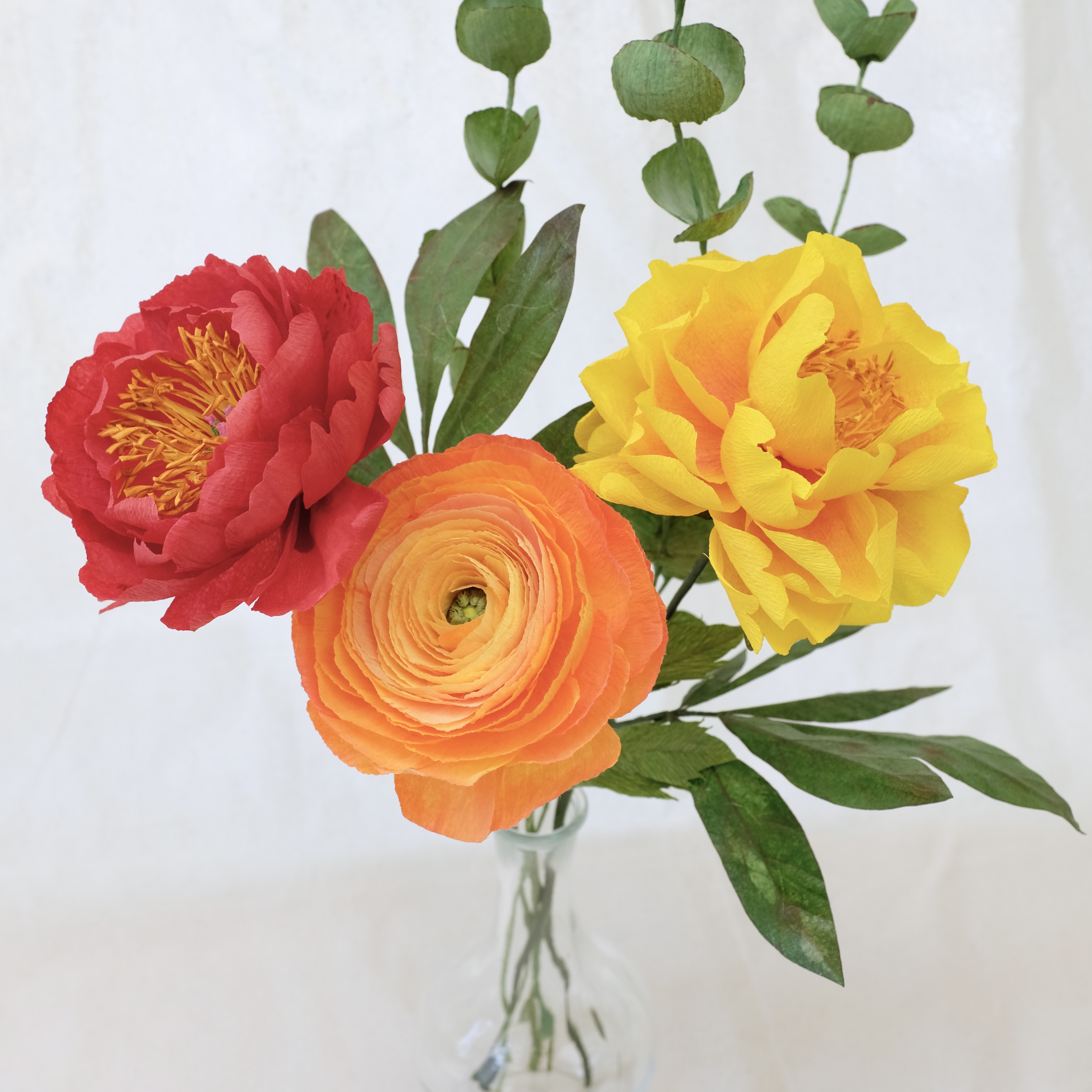 Bouquet de fleurs en papier : pivoine rouge, pivoine jaune,  renoncule orange et trois brins d'eucalyptus