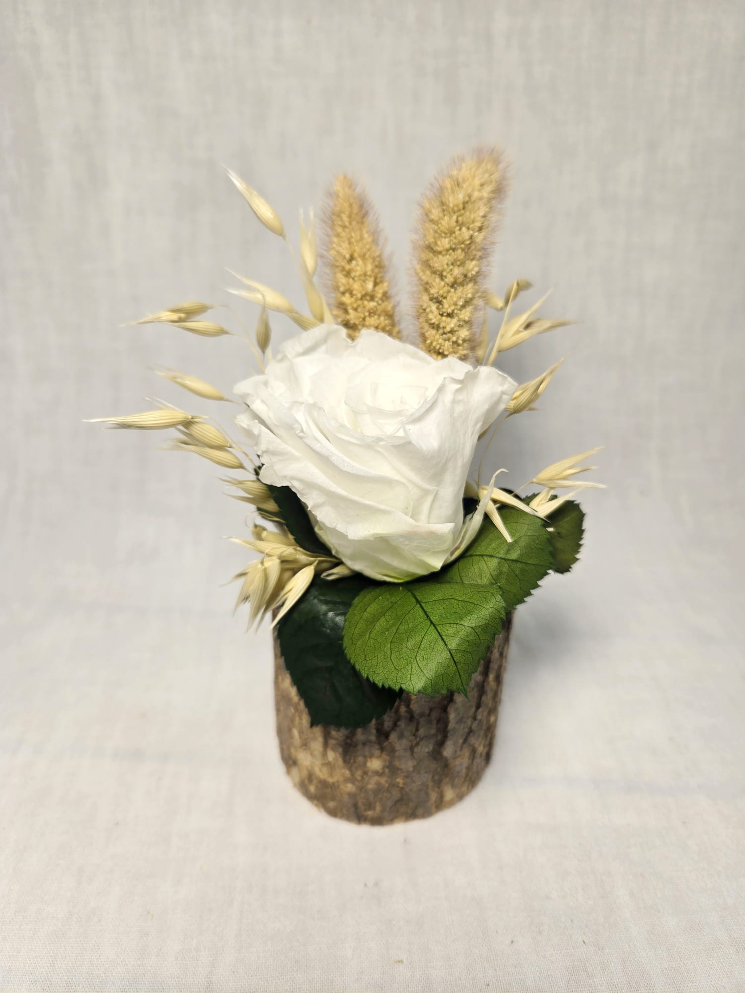 Rose éternelle et fleurs séchées sur bûche en bois