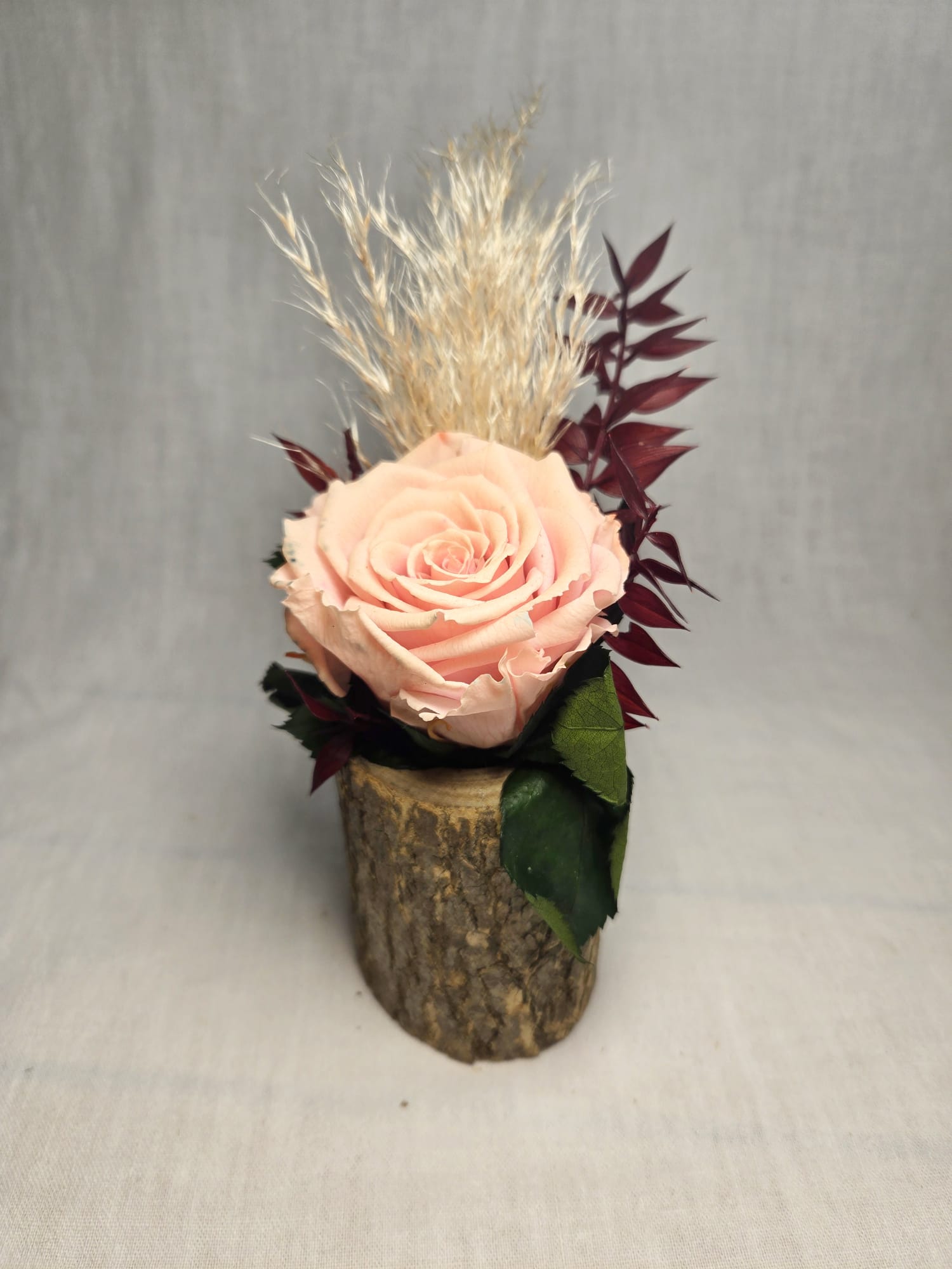 Rose éternelle et fleurs séchées sur bûche en bois