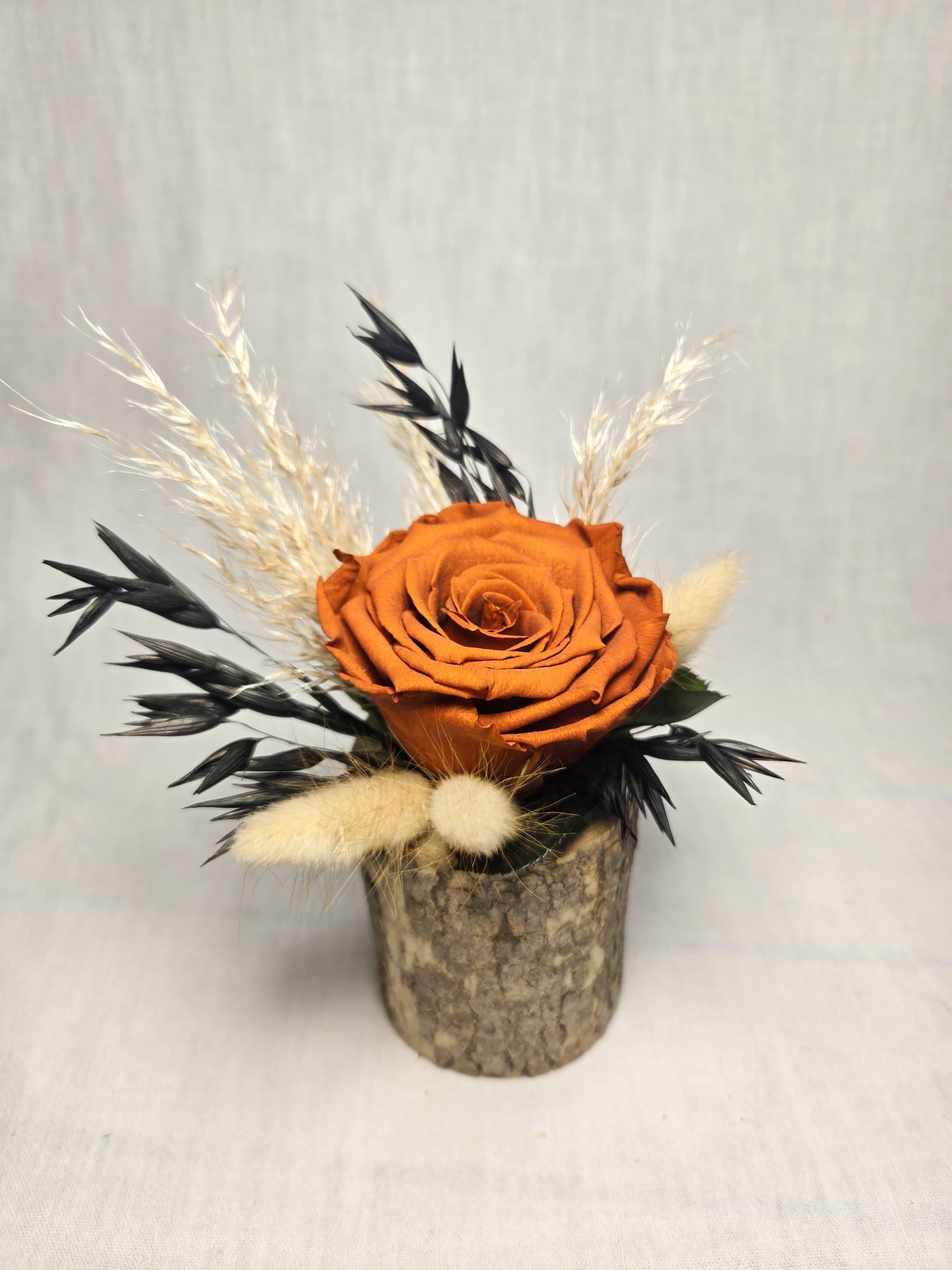 Rose éternelle et fleurs séchées sur bûche en bois