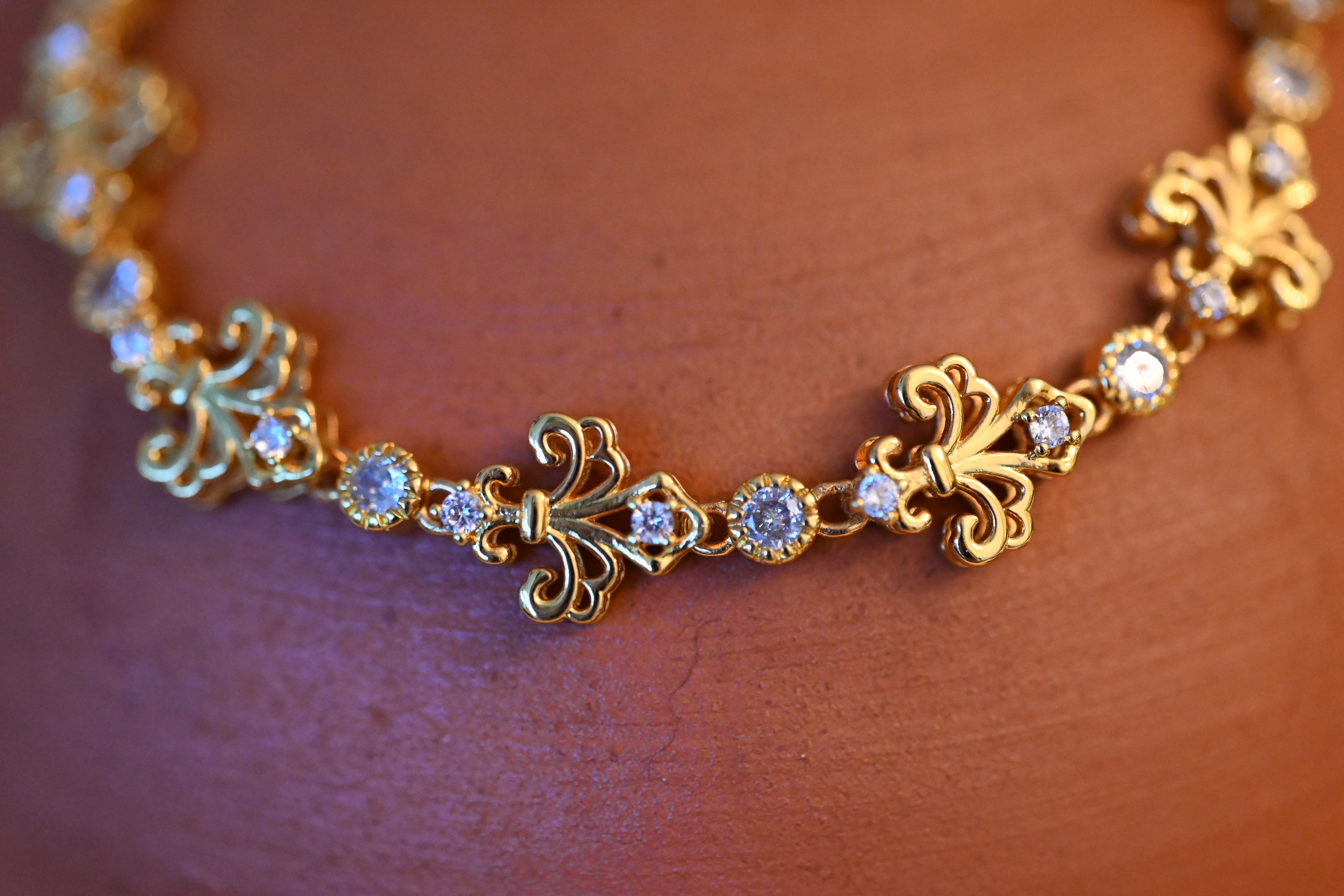Golden bracelet with fleur-de-lis-style zirconia stones