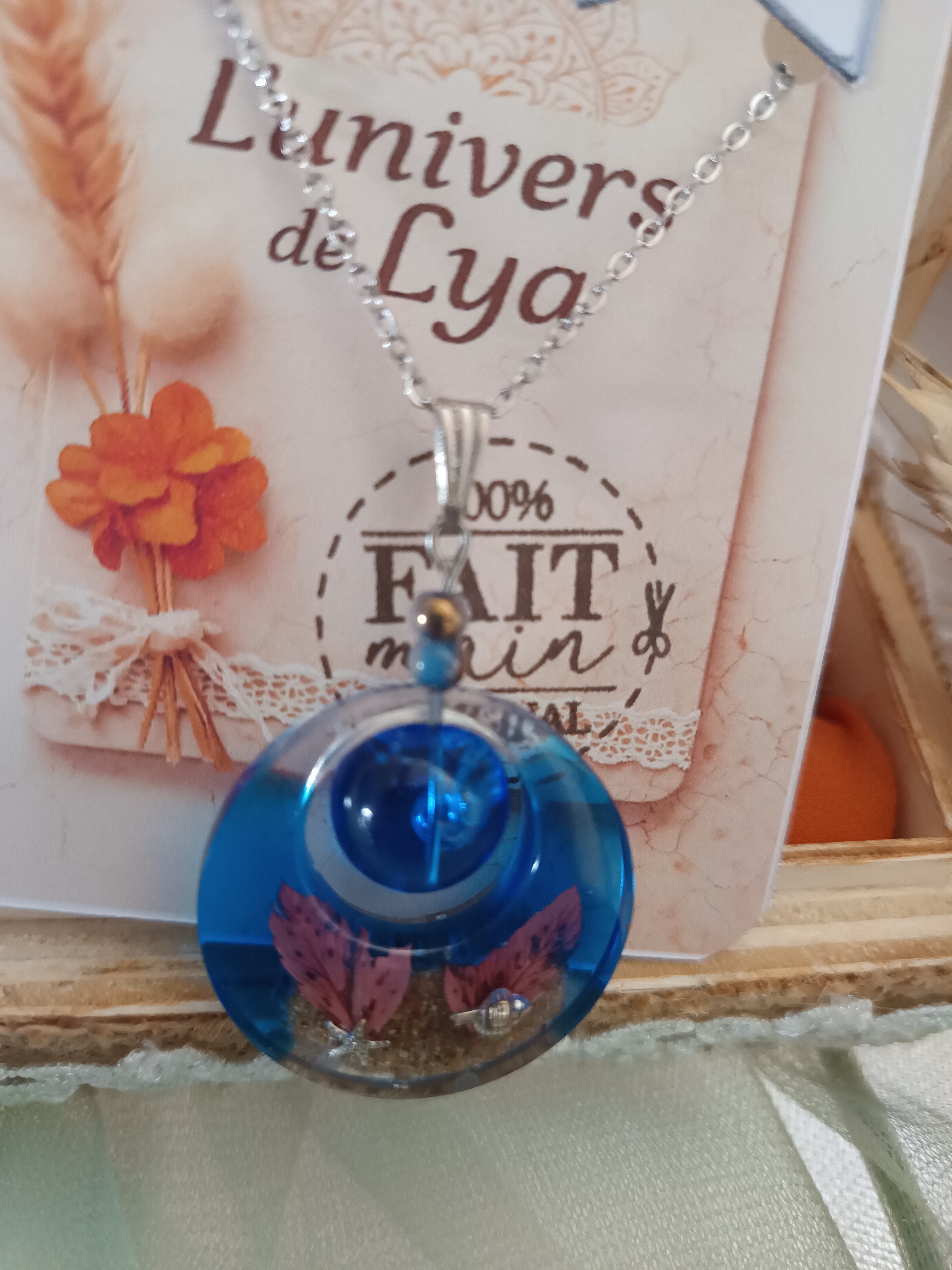 Collier artisanal en résine bleutée avec fleurs séchées – Pendentif rond bohème naturel