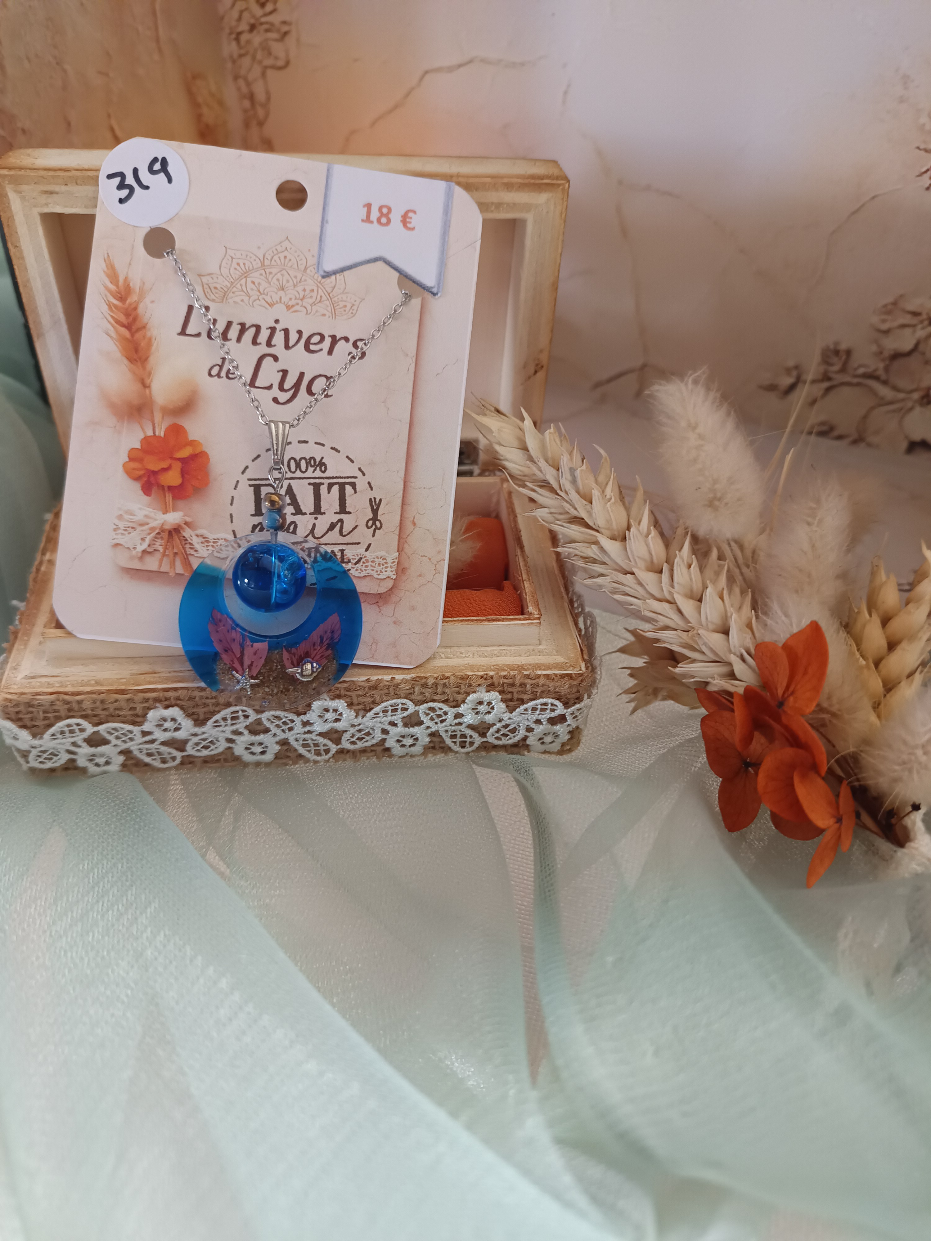 Collier artisanal en résine bleutée avec fleurs séchées – Pendentif rond bohème naturel