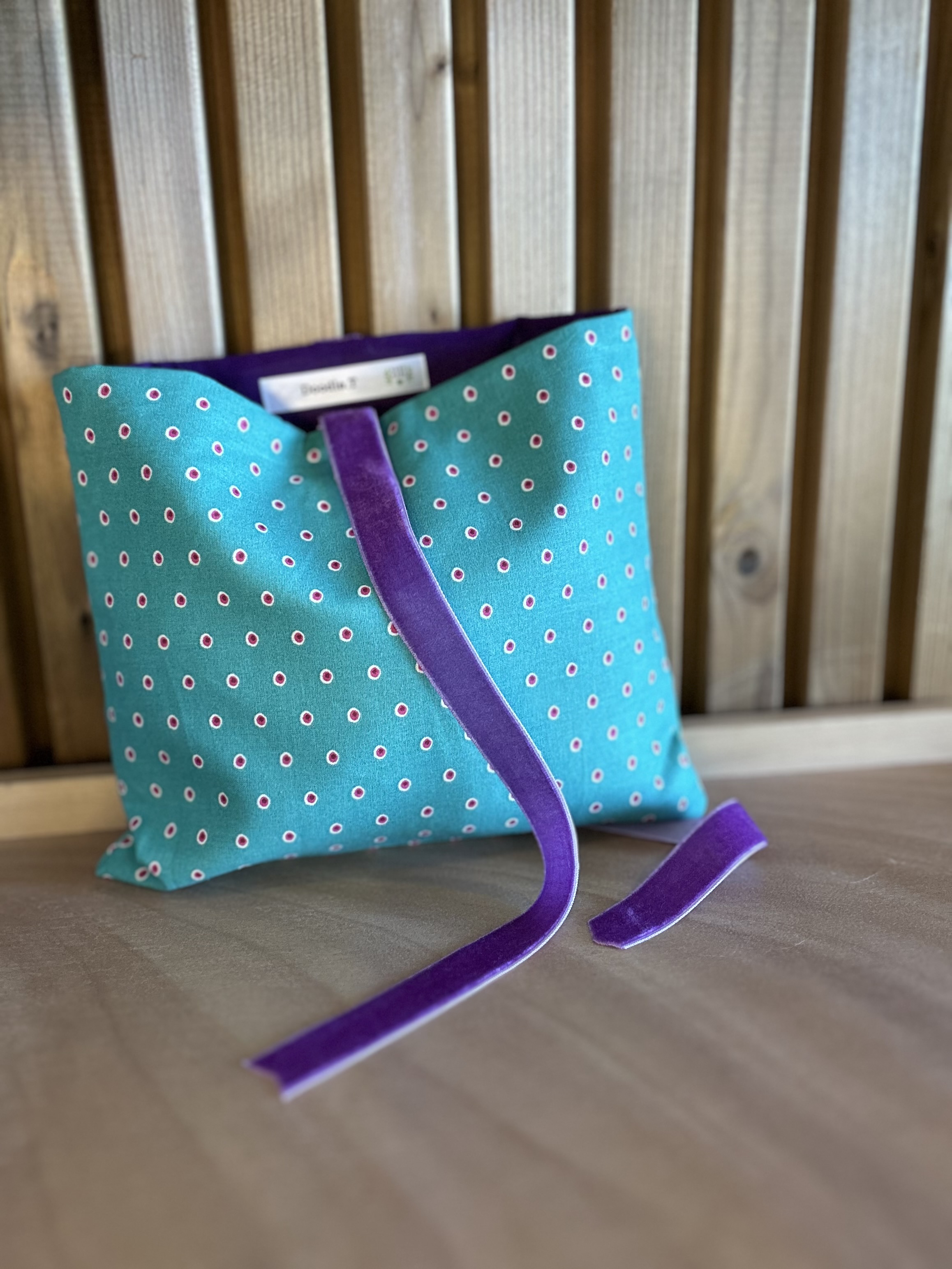 Bolsa de tecido verde e roxo.