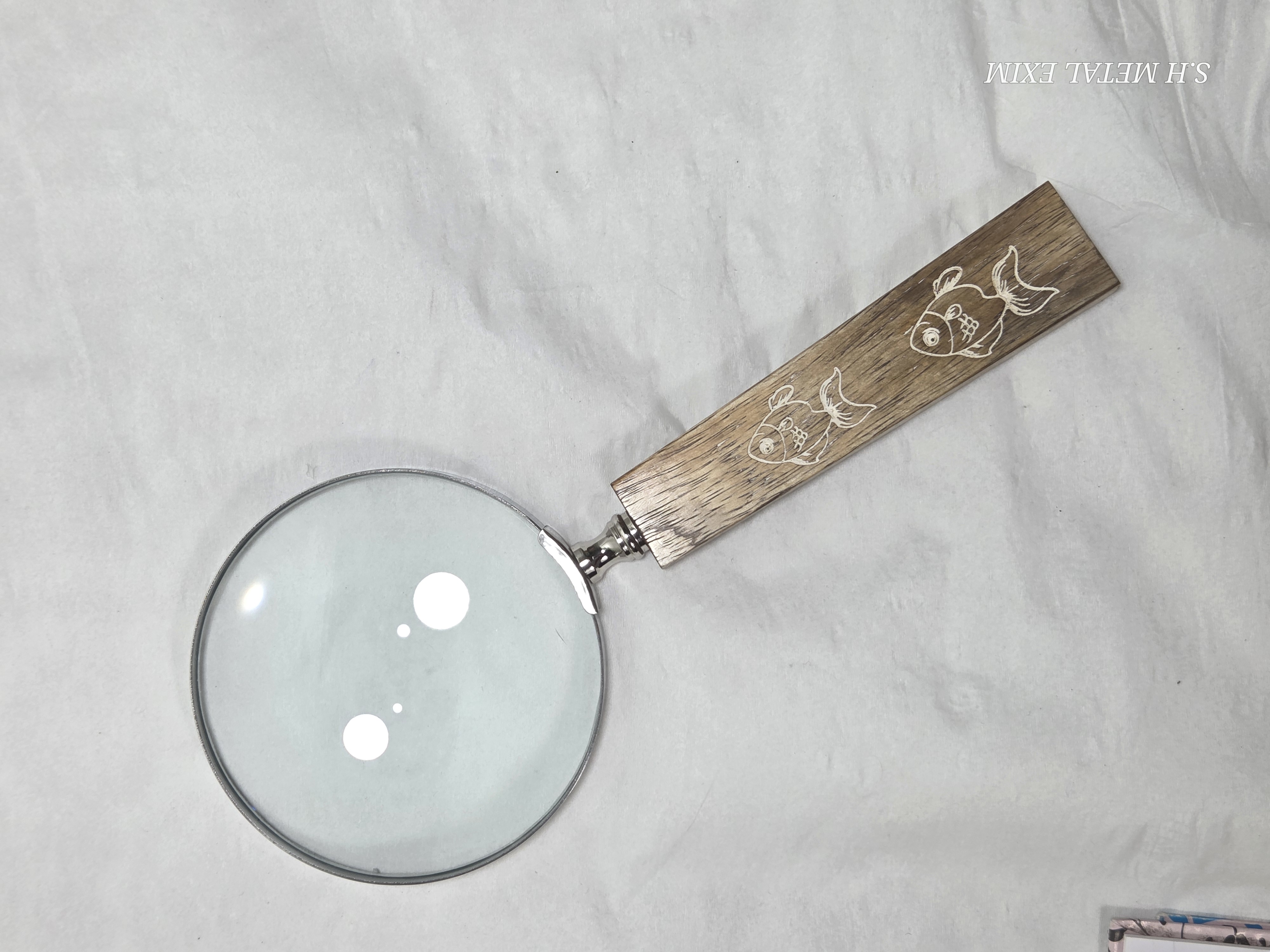 Premium magnifying glass with a wooden handle with printed fish .