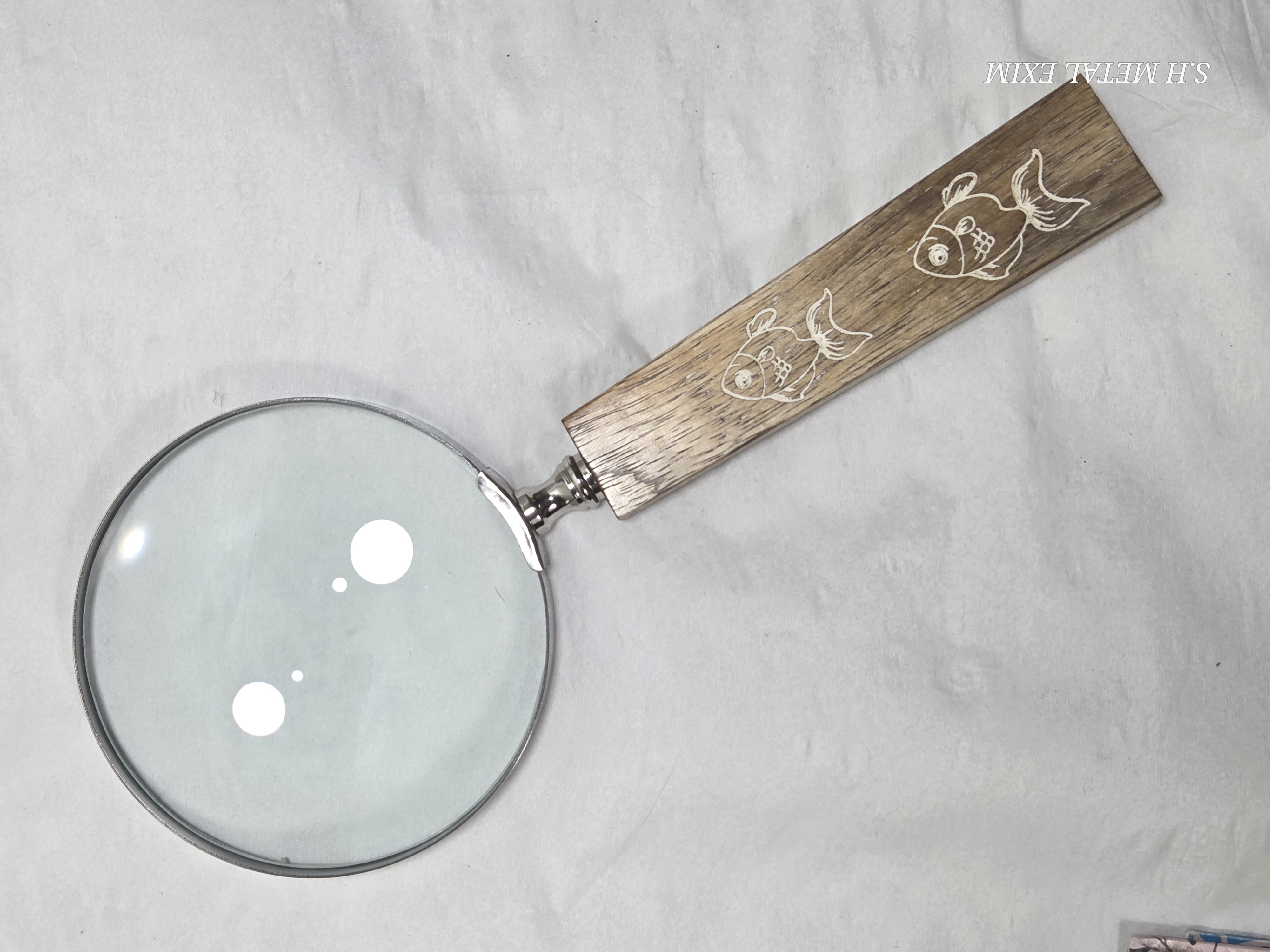 Premium magnifying glass with a wooden handle with printed fish .