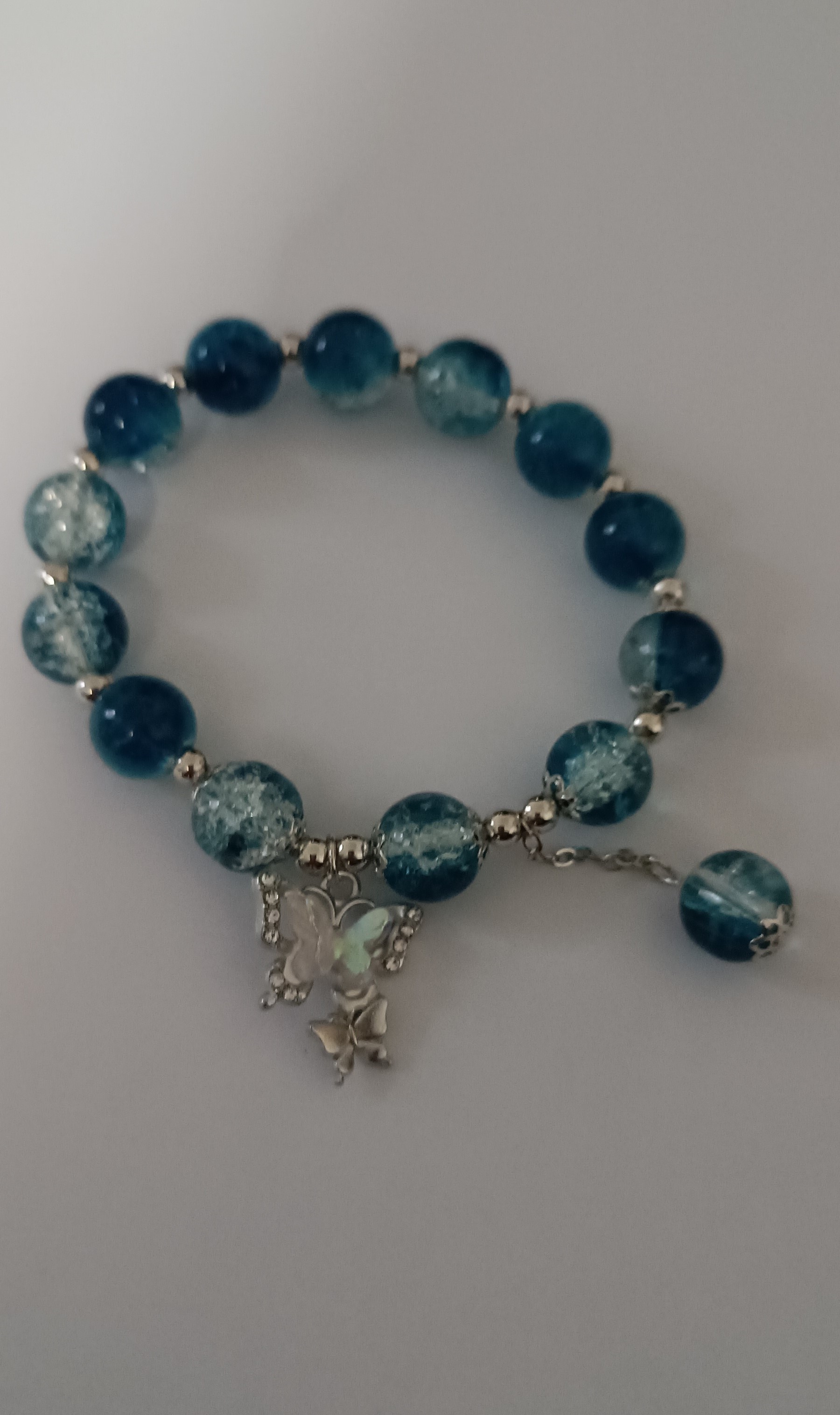 Bracelet élastique en perles bleues et papillon nacré et strass